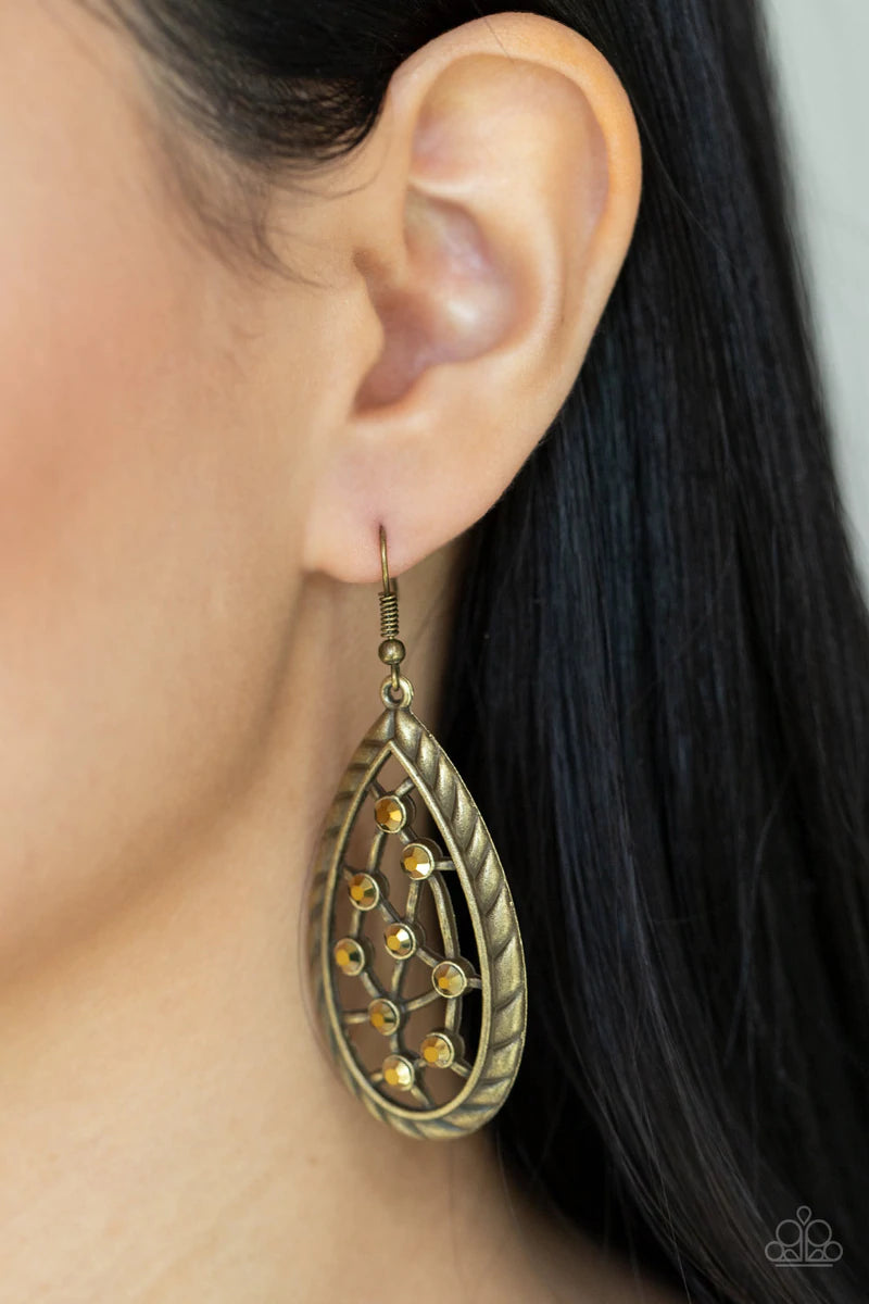 Paparazzi Accessories Industrial Incandescence - Brass A gritty collection of dainty aurum rhinestones adorn hammered brass bars streaking across the airy center of an antiqued textured teardrop, creating a rustic fashion. Earring attaches to a standard f