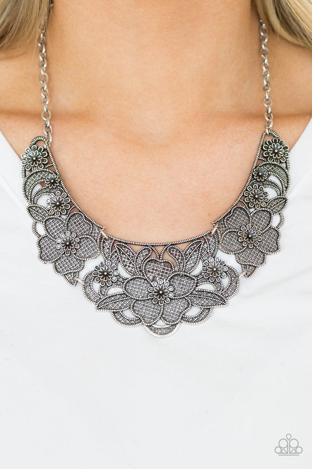 Paparazzi Accessories Petunia Paradise - Silver Featuring lattice-like patterns, shimmery silver flowers bloom below the collar for a seasonal look. Features an adjustable clasp closure. Sold as one individual necklace. Includes one pair of matching earri