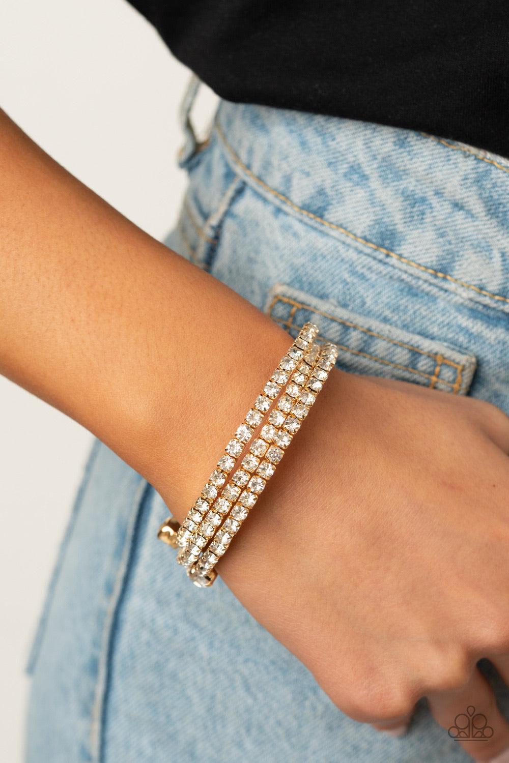 Paparazzi Accessories After Party Princess - Gold Featuring two oversized white rhinestone fittings, a glittery collection of white rhinestone encrusted gold frames are threaded along a gold wire around the wrist, creating a glamorous infinity wrap bracel