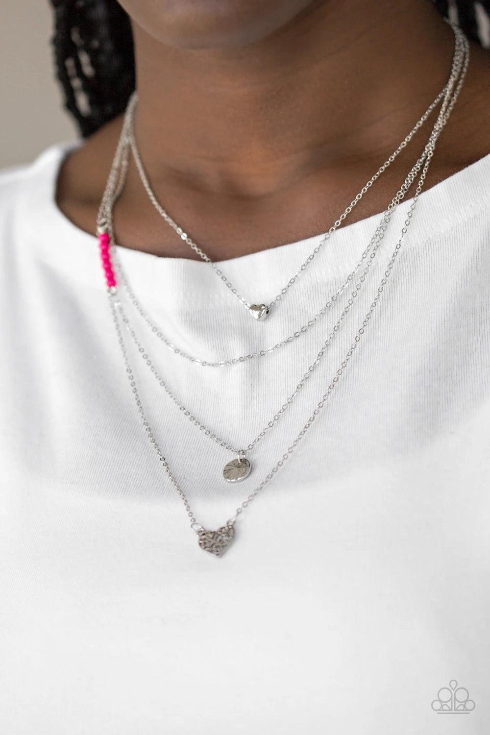 Paparazzi Accessories Gypsy Heart - Pink Shimmery silver layers cascade below the collar. Infused with hints of vivacious pink beading, dainty silver hearts and a delicately hammered silver disc swing from the bottoms of the chains for a whimsical finish.