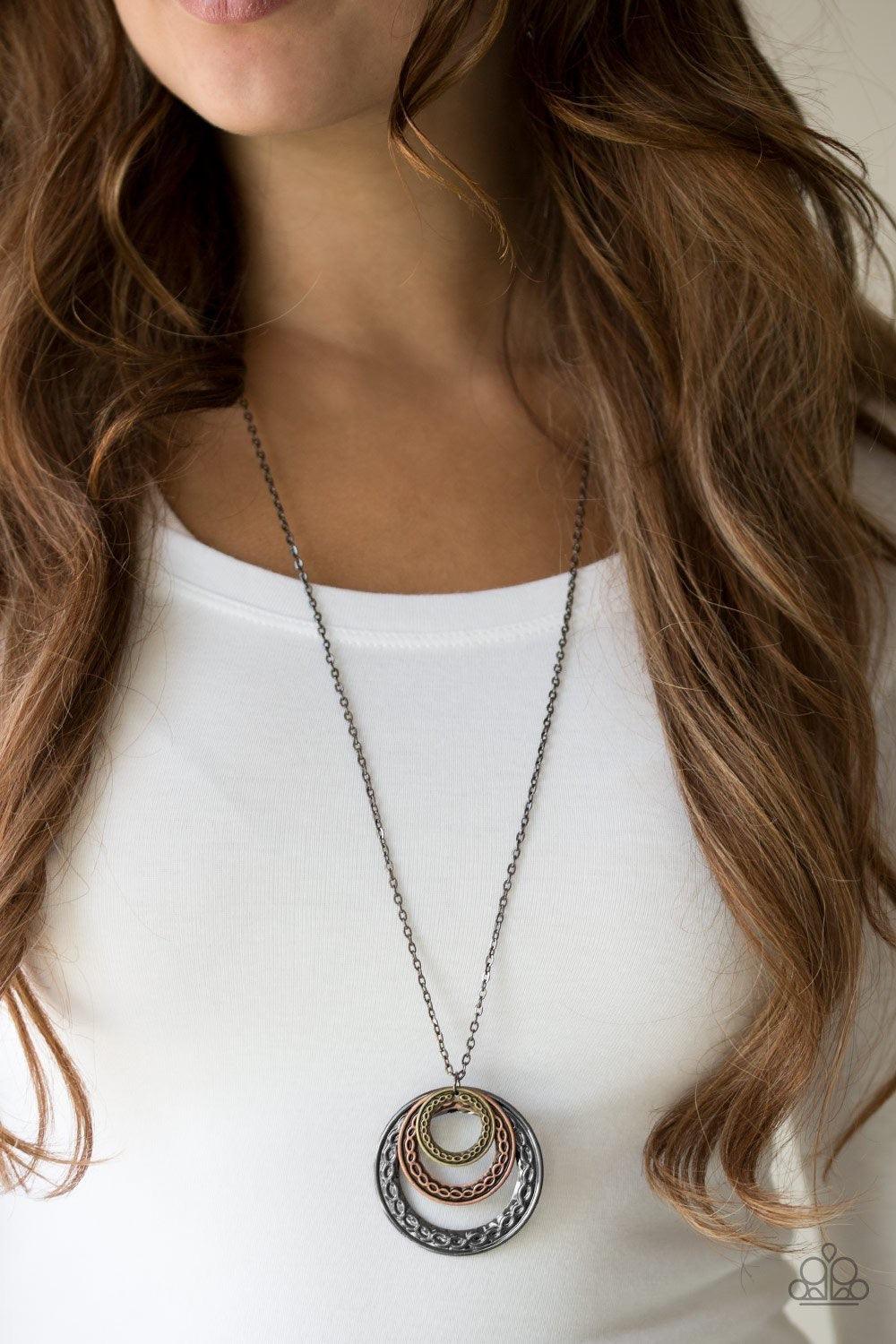 Paparazzi Accessories Savagely She-Wolf - Multi Embossed in swirling tribal detail, brass, copper, and gunmetal frames swing from the bottom of an elongated gunmetal chain, creating an airy stacked pendant. Features an adjustable clasp closure. Jewelry