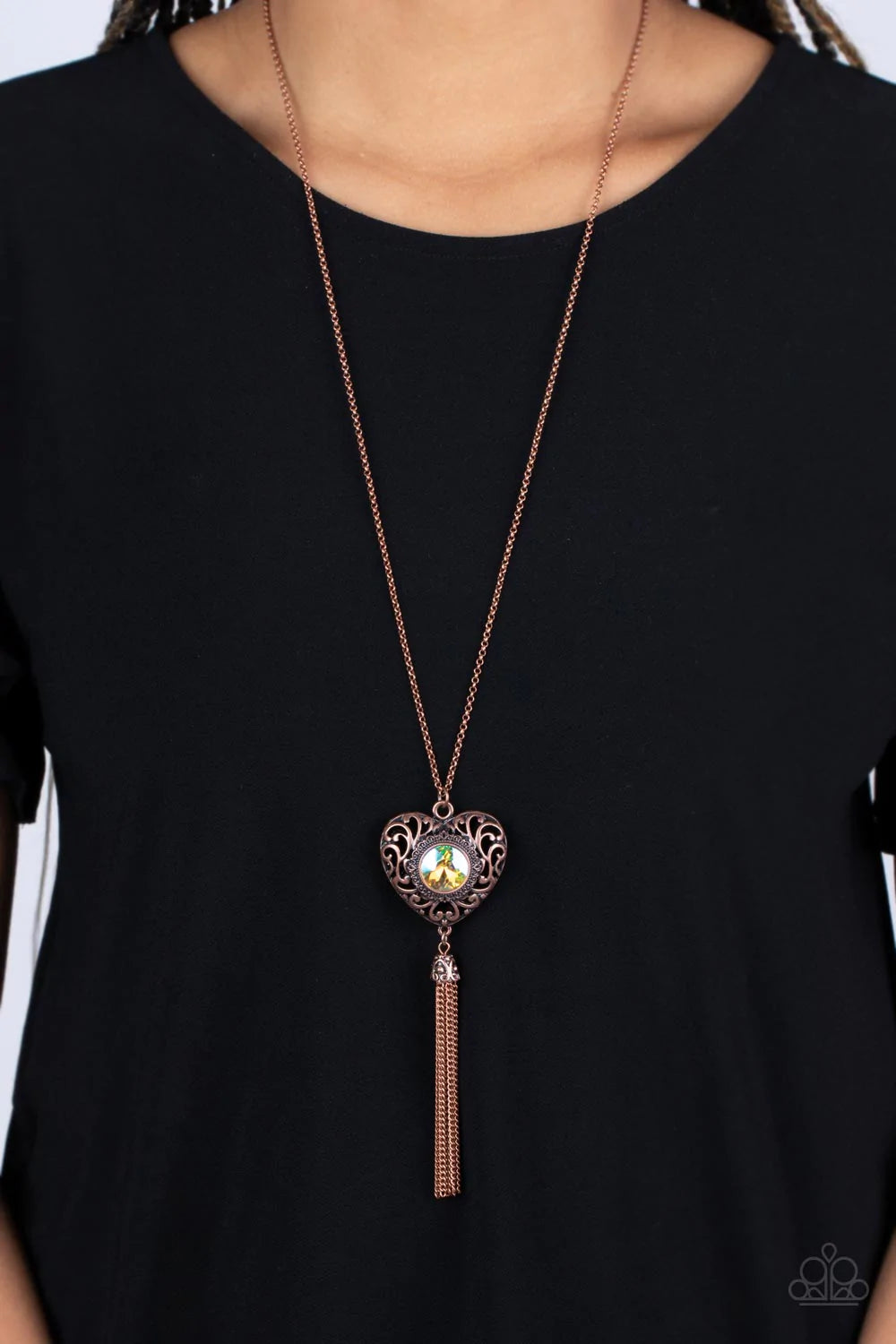 Paparazzi Accessories Prismatic Passion - Copper A magical iridescent peach gem sparkles at the center of a 3-dimensional copper heart. Filled with vine-like filigree, the locket-inspired heart pendant glides along an extended copper chain while a shimmer