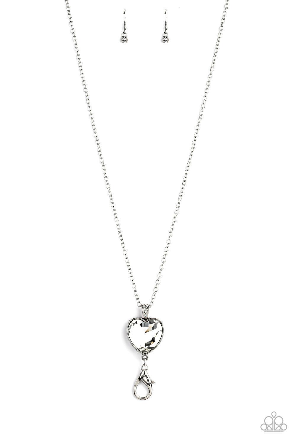 Paparazzi Accessories Lovely Luminosity - Silver *Lanyard Attached to a white rhinestone encrusted fitting, an oversized heart cut gem pendant swings from the bottom of a shimmery silver chain for a charming look. A lobster clasp hangs from the bottom of
