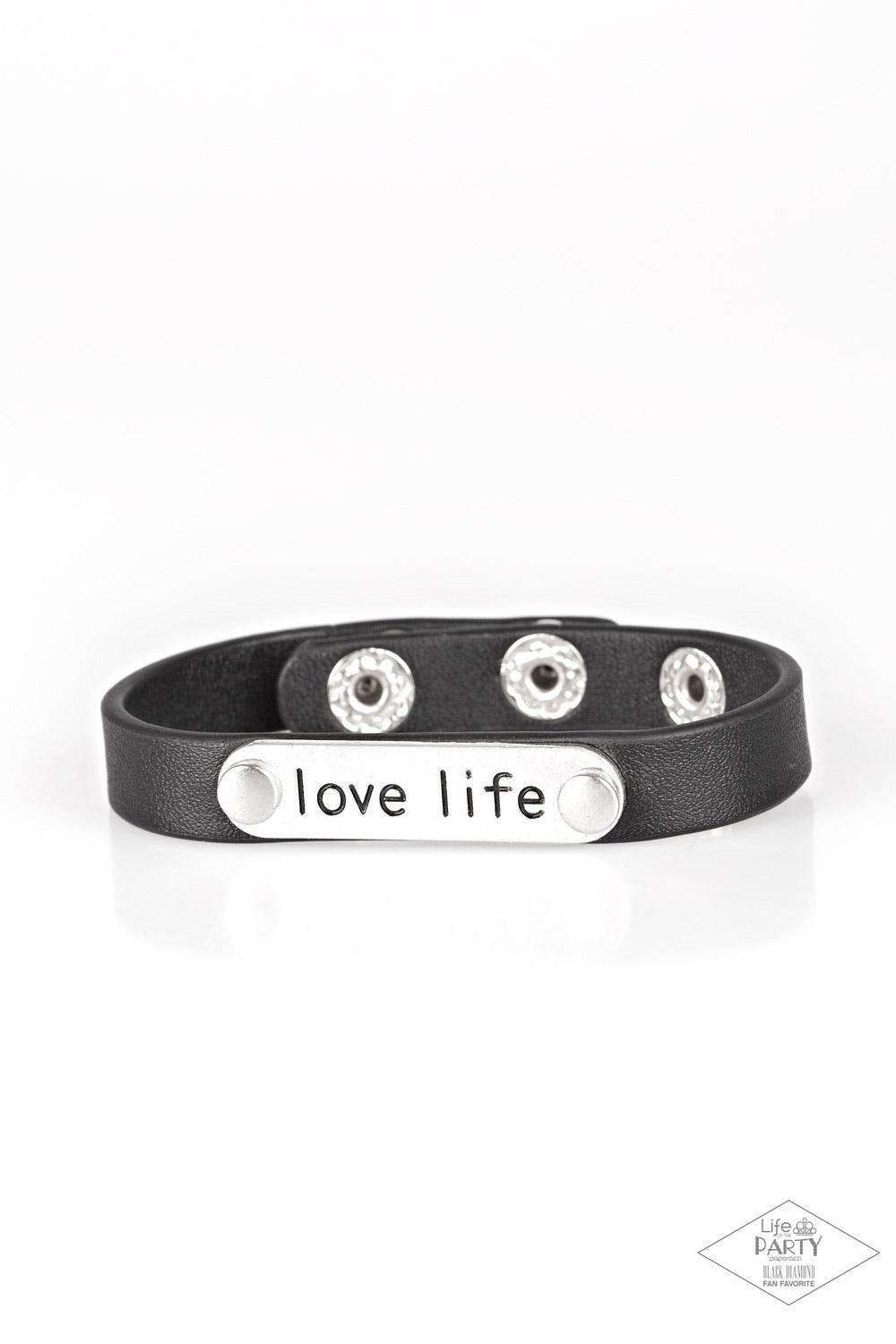 Paparazzi Accessories Love Life - Black A silver plate engraved with the inspirational phrase “love life” is studded in place along a skinny strip of black leather. Brushed in a shiny finish, the dainty band wraps around the wrist in a simply seasonal sty