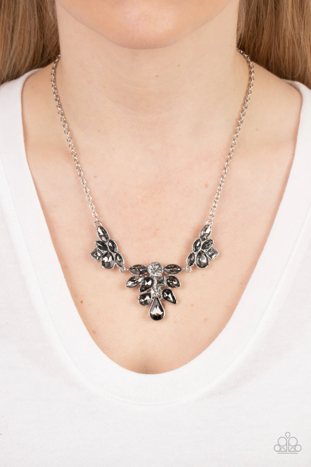 Paparazzi Accessories Completely Captivated - Silver Varying in cut and shimmer, bubbly clusters of mismatched white and smoky rhinestones coalesce into three sparkly frames for a captivating statement below the collar. Features an adjustable clasp closur