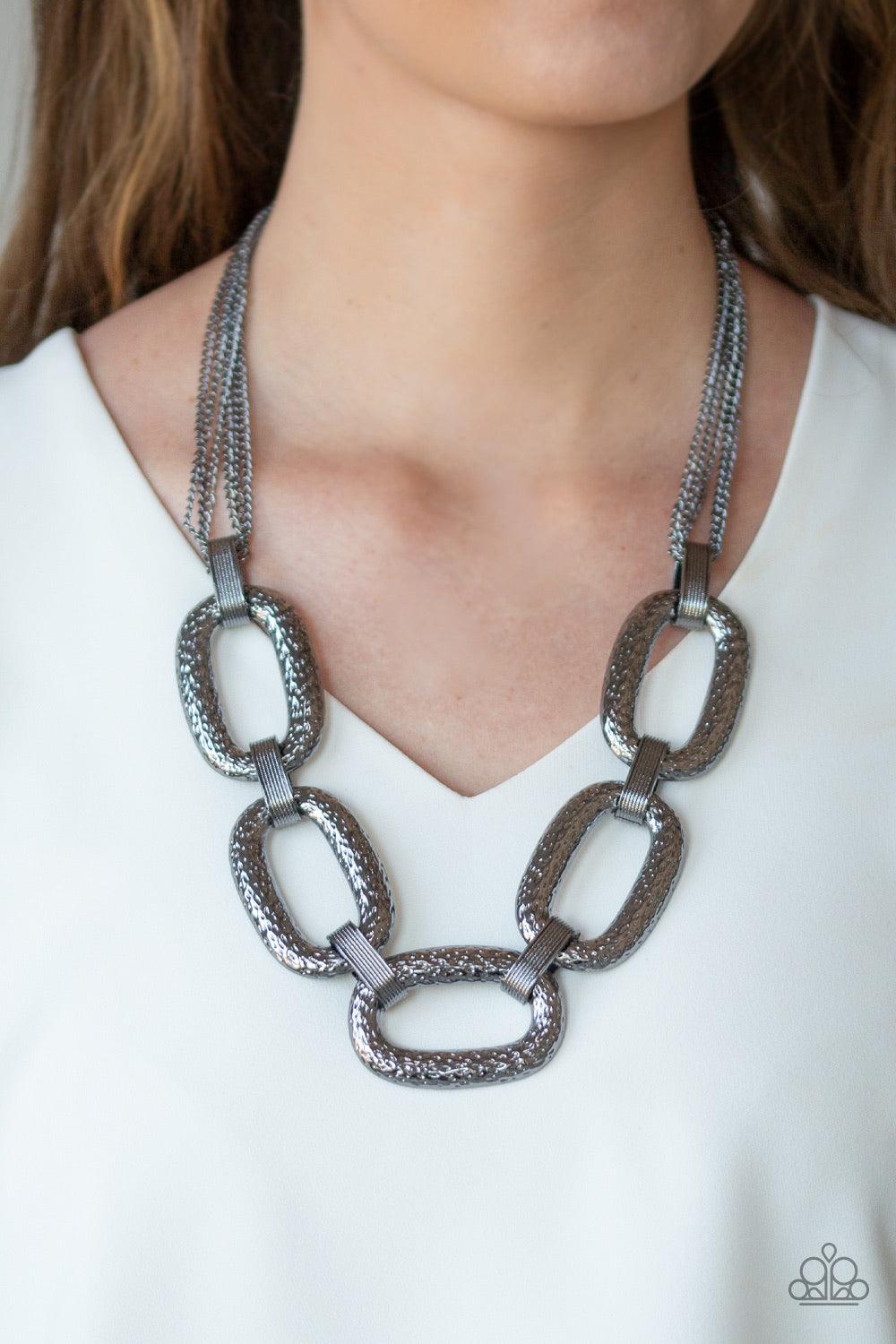 Paparazzi Accessories Take Charge - Black Delicately hammered in blinding shimmer, oversized shiny gunmetal chain links and textured fittings connect below the collar. Suspended from strands of gunmetal chains, the bold links catch and reflect the light f