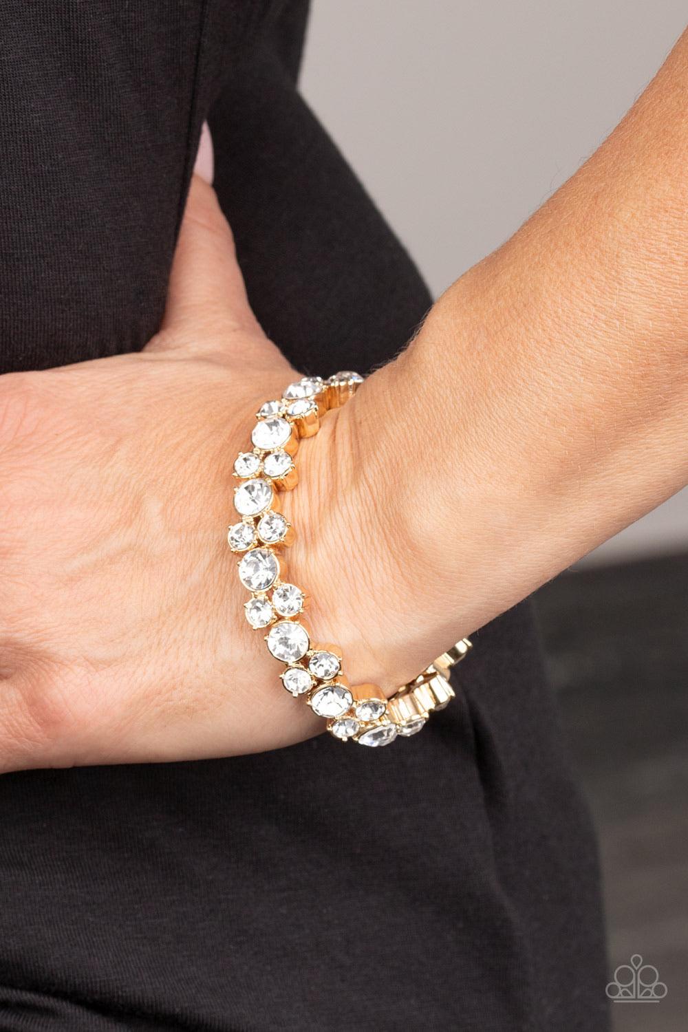 Paparazzi Accessories Here Comes the BRIBE - Gold Featuring sleek gold frames, trios of glittery white rhinestones are threaded along stretchy bands around the wrist for a timeless shimmer. Sold as one individual bracelet. Jewelry