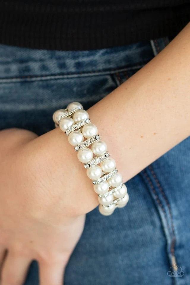 Paparazzi Accessories Glowing Glam - White Pairs of pearly white beads and white rhinestone encrusted silver fittings are threaded along an invisible wire around the wrist for a refined flair. Features an adjustable clasp closure. Sold as one individual b
