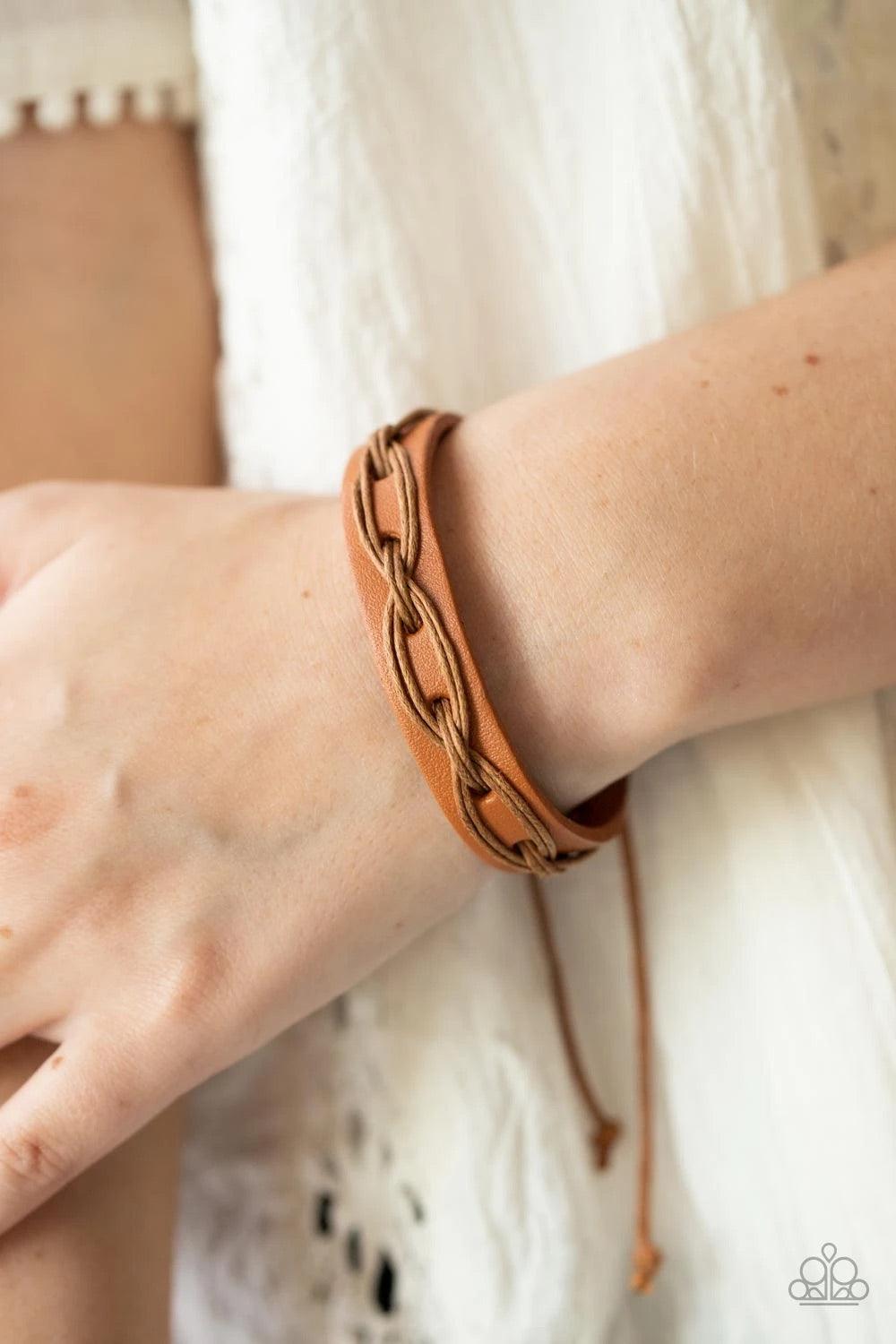 Paparazzi Accessories Macho Mystery - Brown Brown cording is interwoven across the top of a light brown leather band creating an edgy crisscrossed texture around the wrist. Features an adjustable sliding knot closure. Sold as one individual bracelet. Jewe