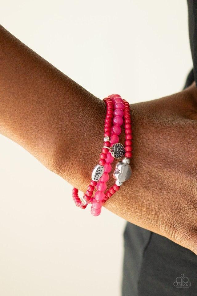 Paparazzi Accessories Really Romantic - Pink An array of glassy and polished pink beads are threaded along stretchy bands. Infused with silver accents, a collection of silver heart charms and a bead spelling out the word, "love", adorn the beaded strands