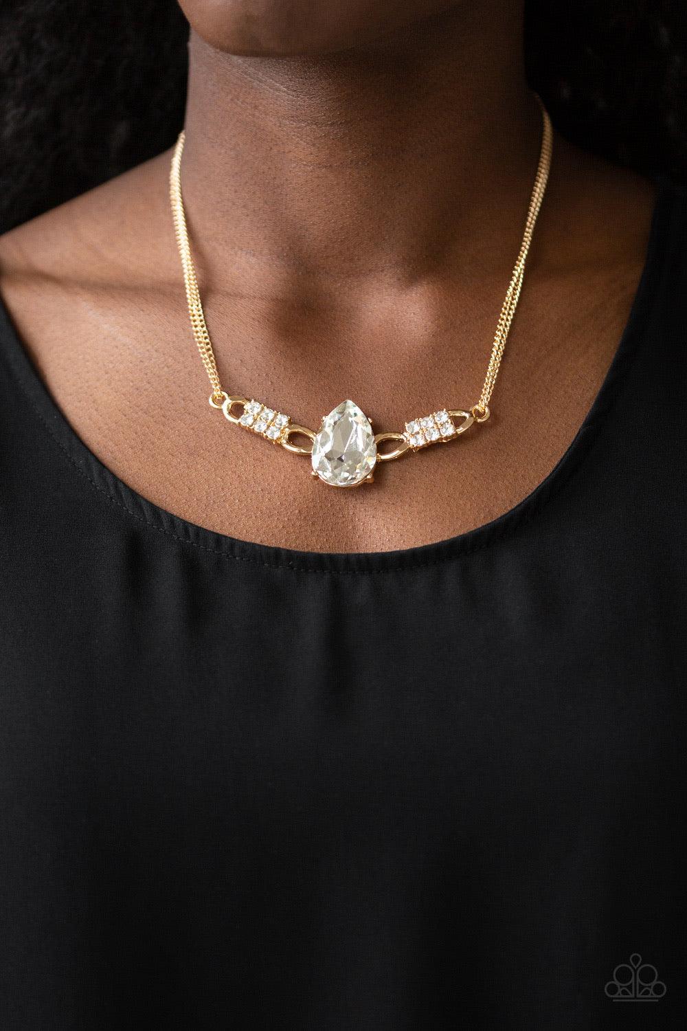 Paparazzi Accessories Way To Make An Entrance ~Gold Cut into an alluring teardrop, an oversized white rhinestone gem attaches to bold gold frames radiating with glassy white rhinestones. The dramatic pendant attaches to doubled gold chains, swinging horiz