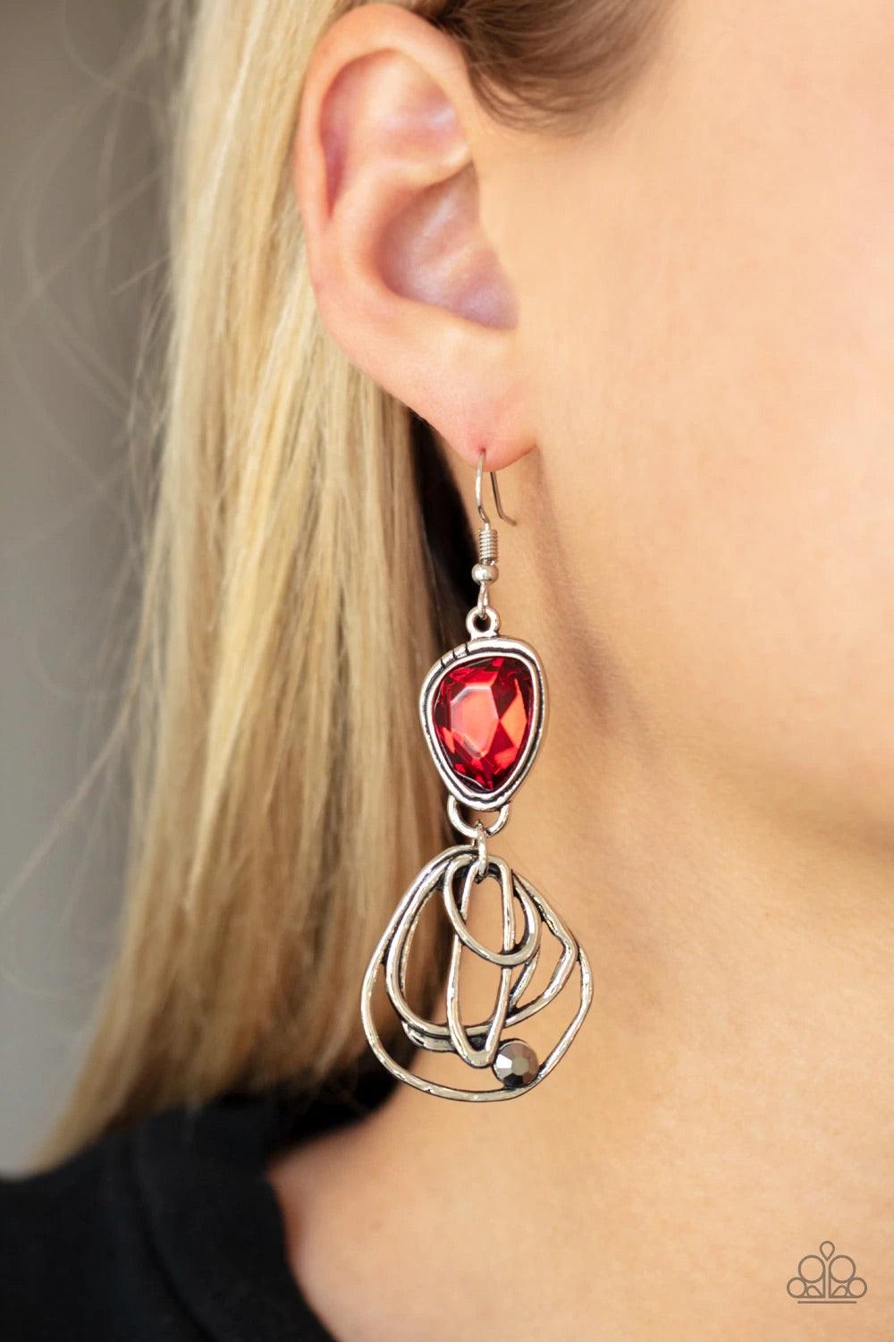 Paparazzi Accessories Galactic Drama - Red Encased in a stacked silver frame, an asymmetrical red gem gives way to a dizzyingly abstract silver frame dotted with a single hematite rhinestone for an edgy finish. Earring attaches to a standard fishhook fitt