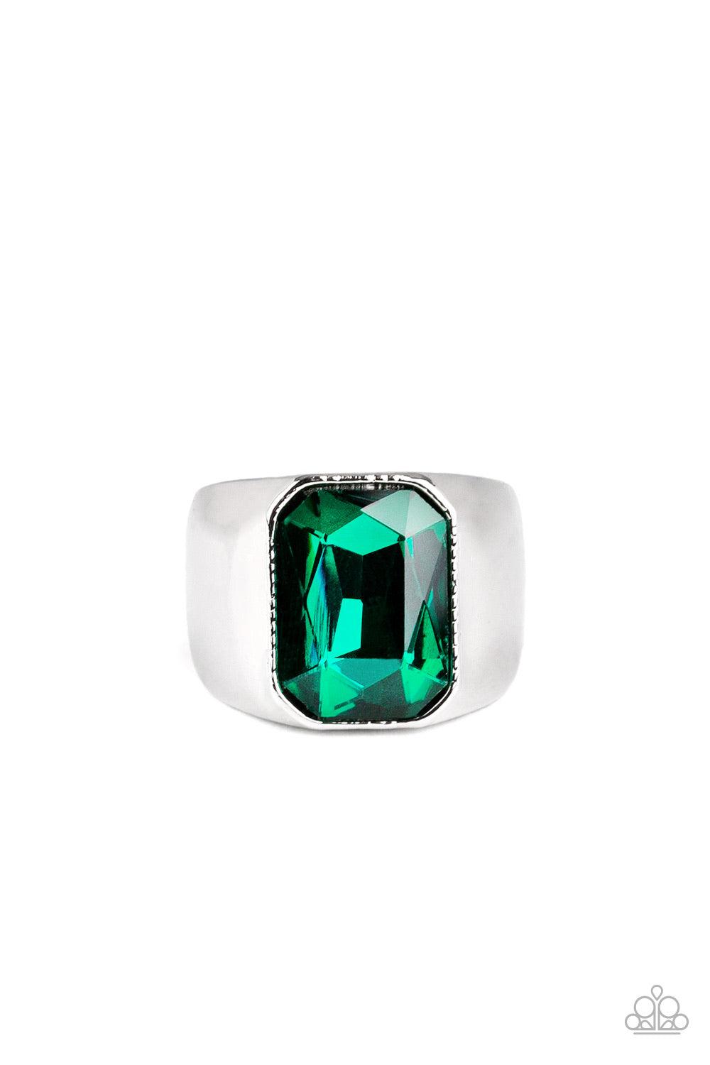 Paparazzi Accessories Scholar - Green Featuring a kingly emerald style cut, an oversized green rhinestone is pressed into the center of a glistening silver band for a statement look. Features a stretchy band for a flexible fit. Jewelry