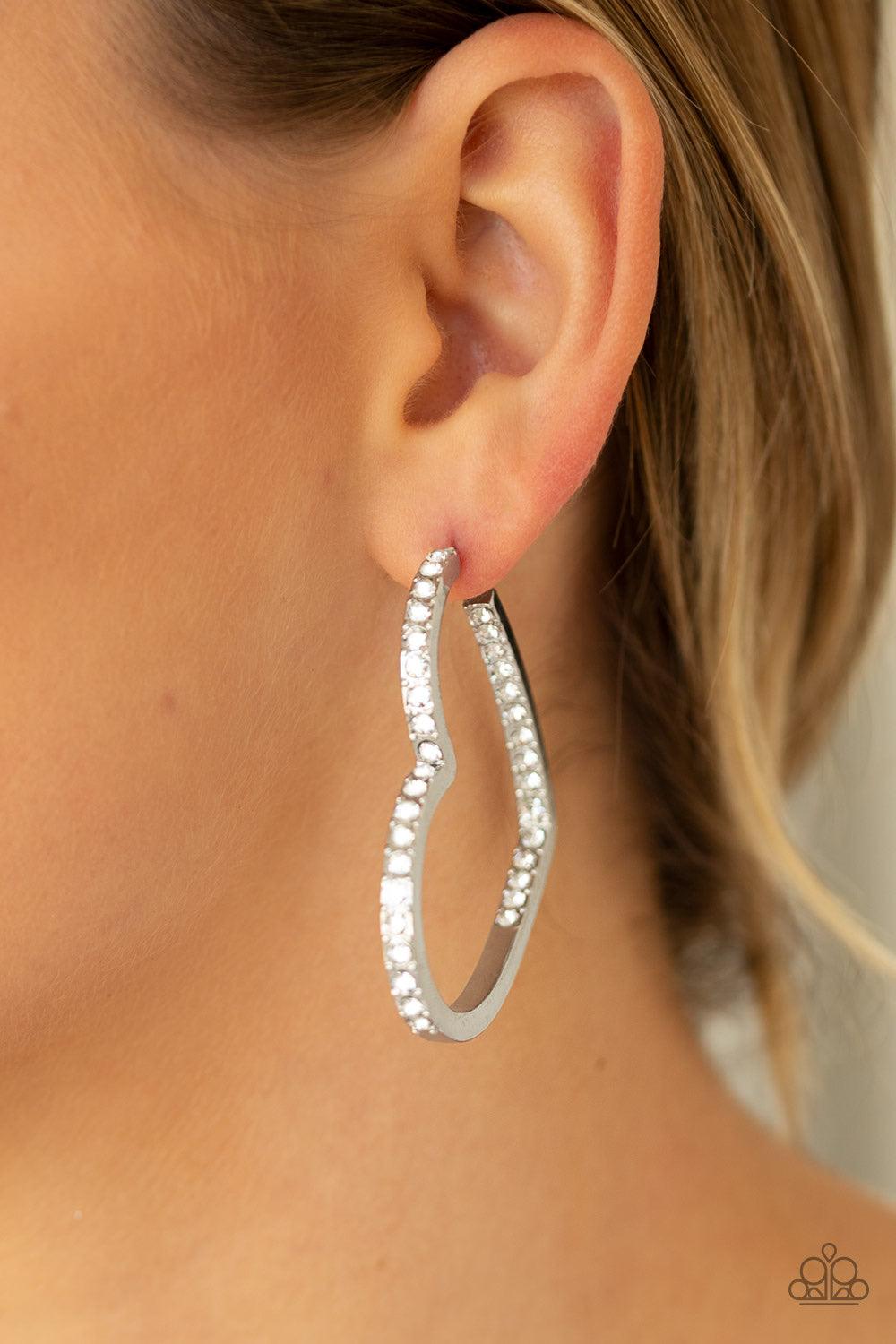Paparazzi Accessories Heartbreaker - White Encrusted in sections of glittery white rhinestones, a glistening silver hoop curls into a charming heart shape for a heart-stopping look. Earring attaches to a standard post fitting. Hoop measures approximately