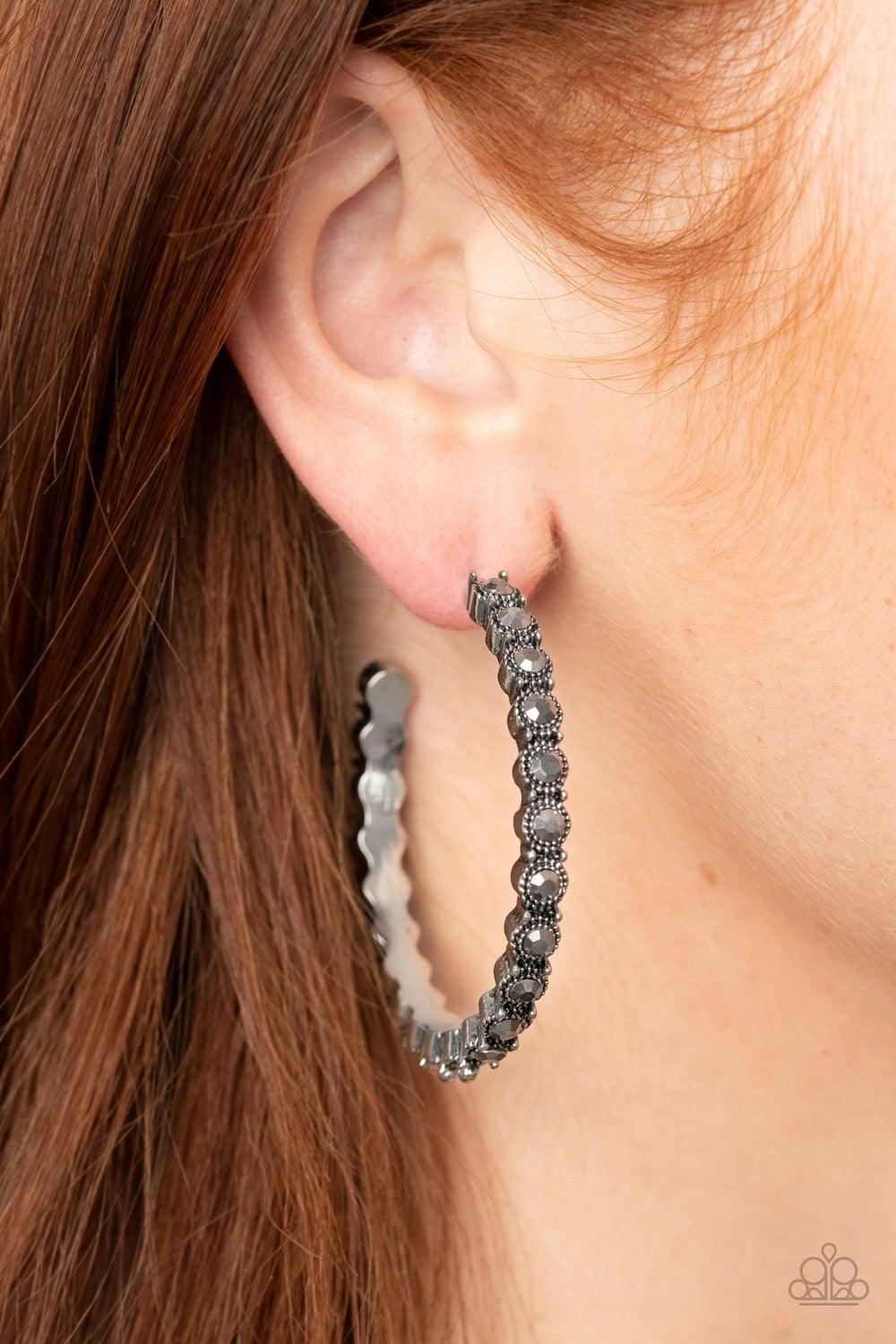 Paparazzi Accessories Rhinestone Studded Sass - Silver The front half of an ornately studded silver hoop is encrusted in smoky hematite rhinestones, adding a splash of exaggerated sparkle to the sassy display. Earring attaches to a standard post fitting.