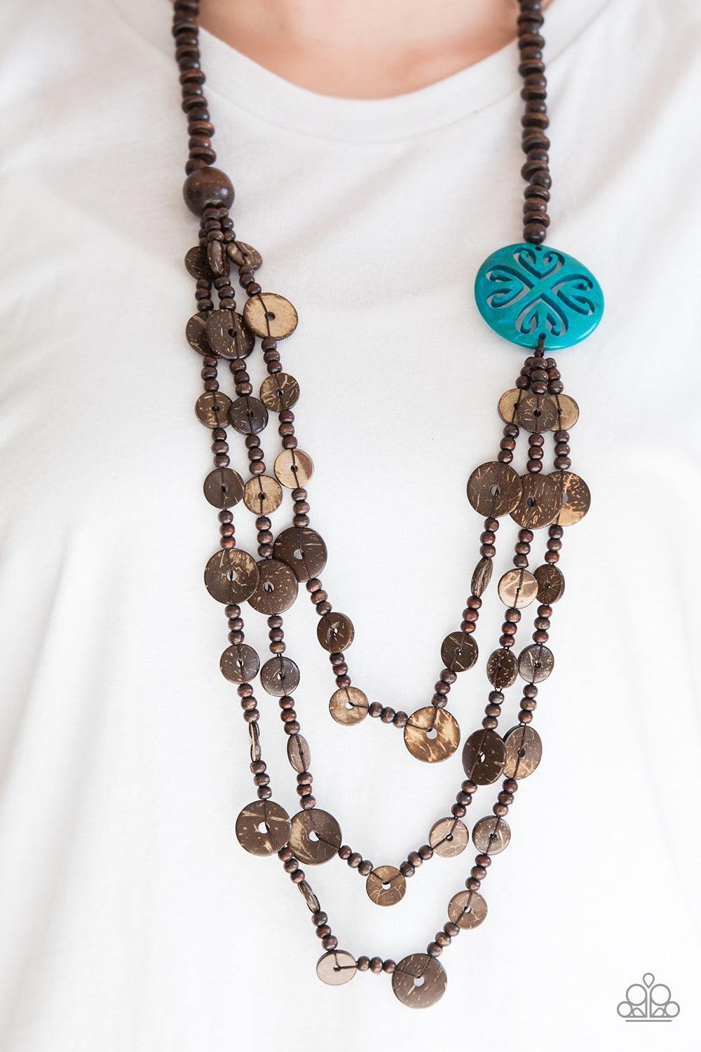 Paparazzi Accessories Jungle Jive - Blue Mismatched brown wooden beads are threaded along a shiny brown string, creating summery layers across the chest. Featuring a whimsical floral pattern, a dramatic blue wooden bead adorns one side for a seasonal fini