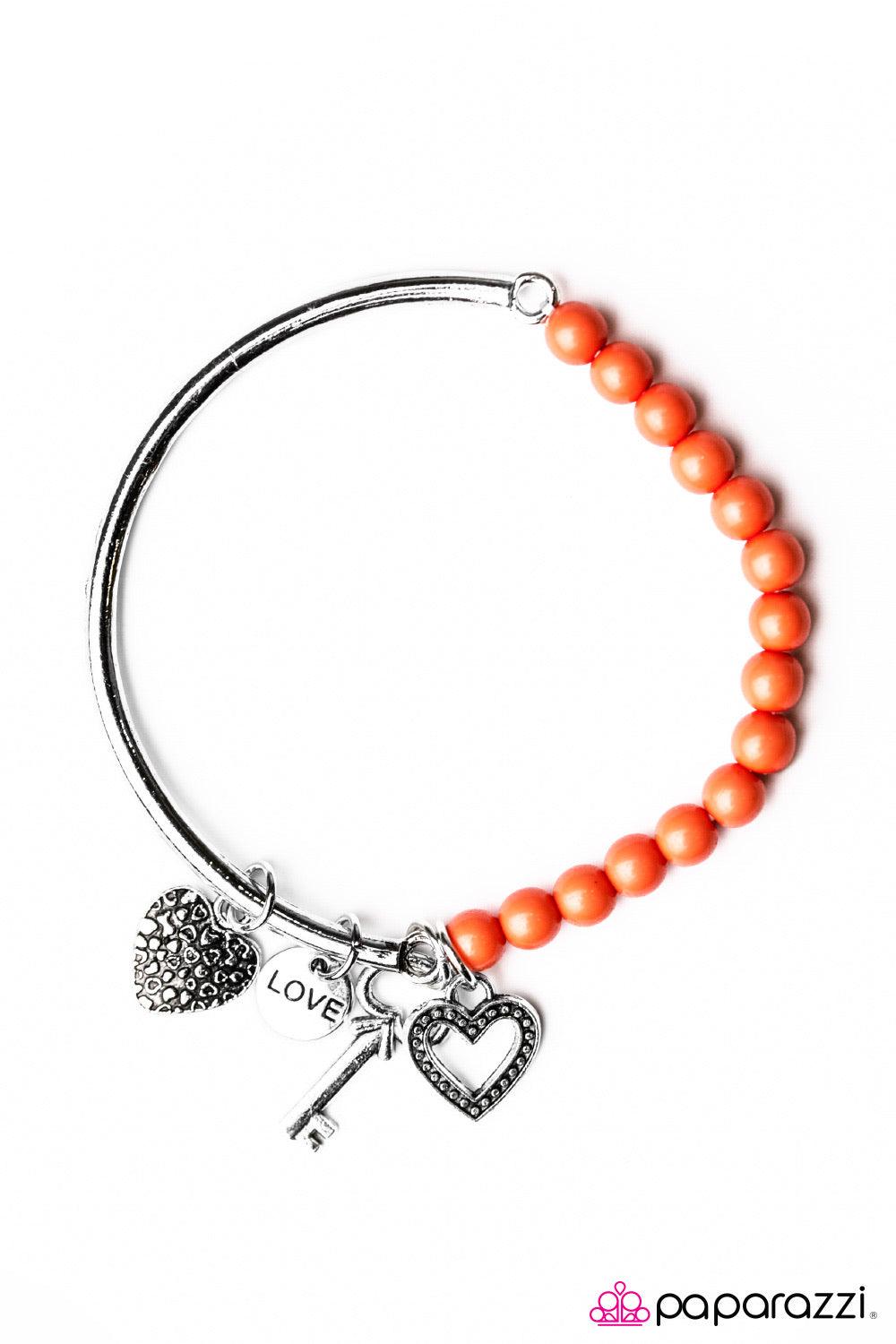 Paparazzi Accessories You Hold The Key ~Orange Threaded through an elastic stretchy band, orange beading connects to a silver bar around the wrist. Brushed in an antiqued shimmer, silver hearts, a key, and charm engraved in the word “love” slides along th