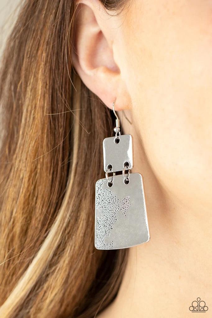 Paparazzi Accessories Tagging Along - Silver Stamped in an abstract pattern, a flared silver plate links to the bottom of a square silver frame, creating a rustic lure. Earring attaches to a standard fishhook fitting. Sold as one pair of earrings. Jewelry