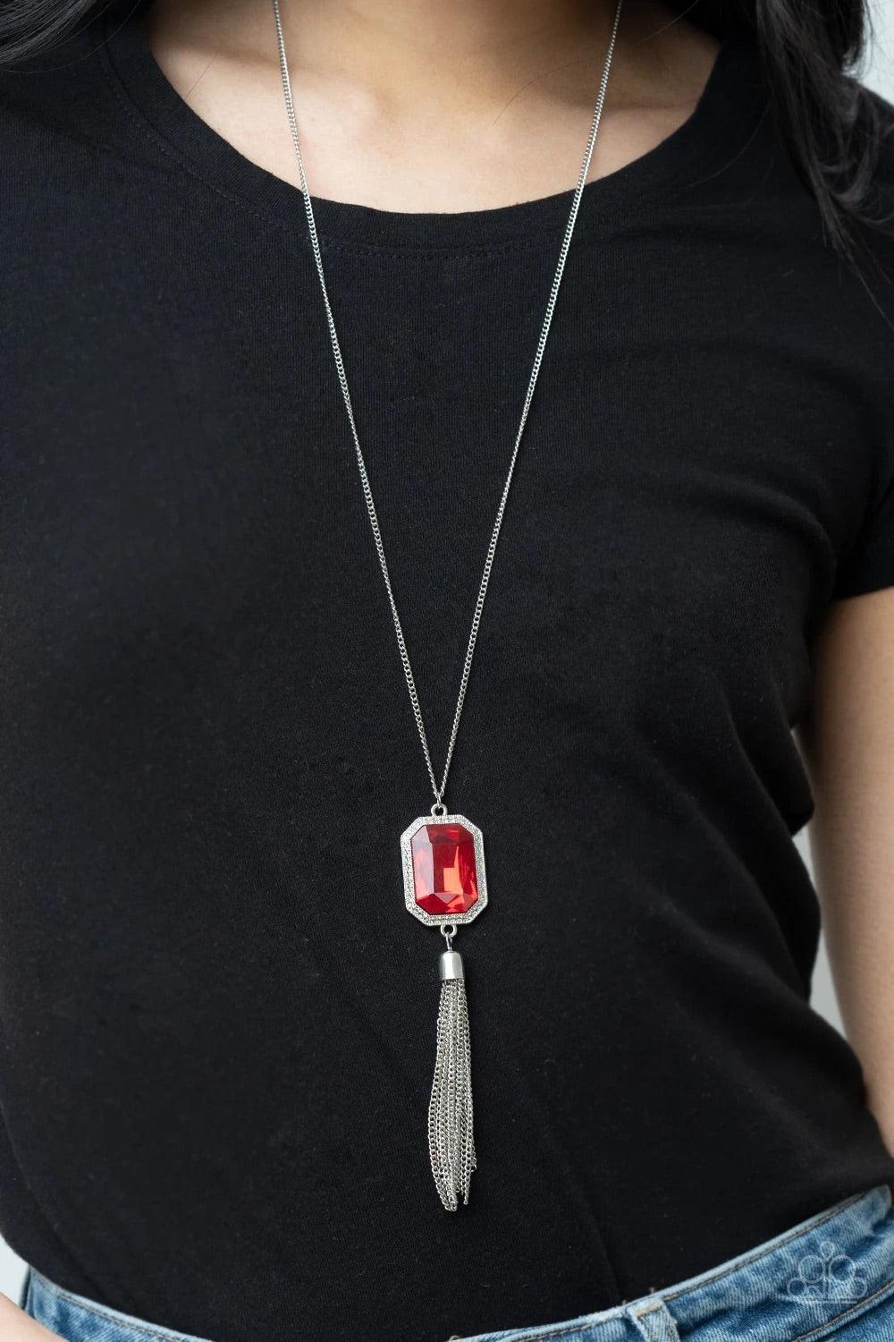 Paparazzi Accessories Blissed Out Opulence - Red An impressive red emerald cut gem is pressed into the center of a silver studded frame, creating an ethereal pop of color at the bottom of a lengthened silver chain. A silver chain tassel swings from the bo