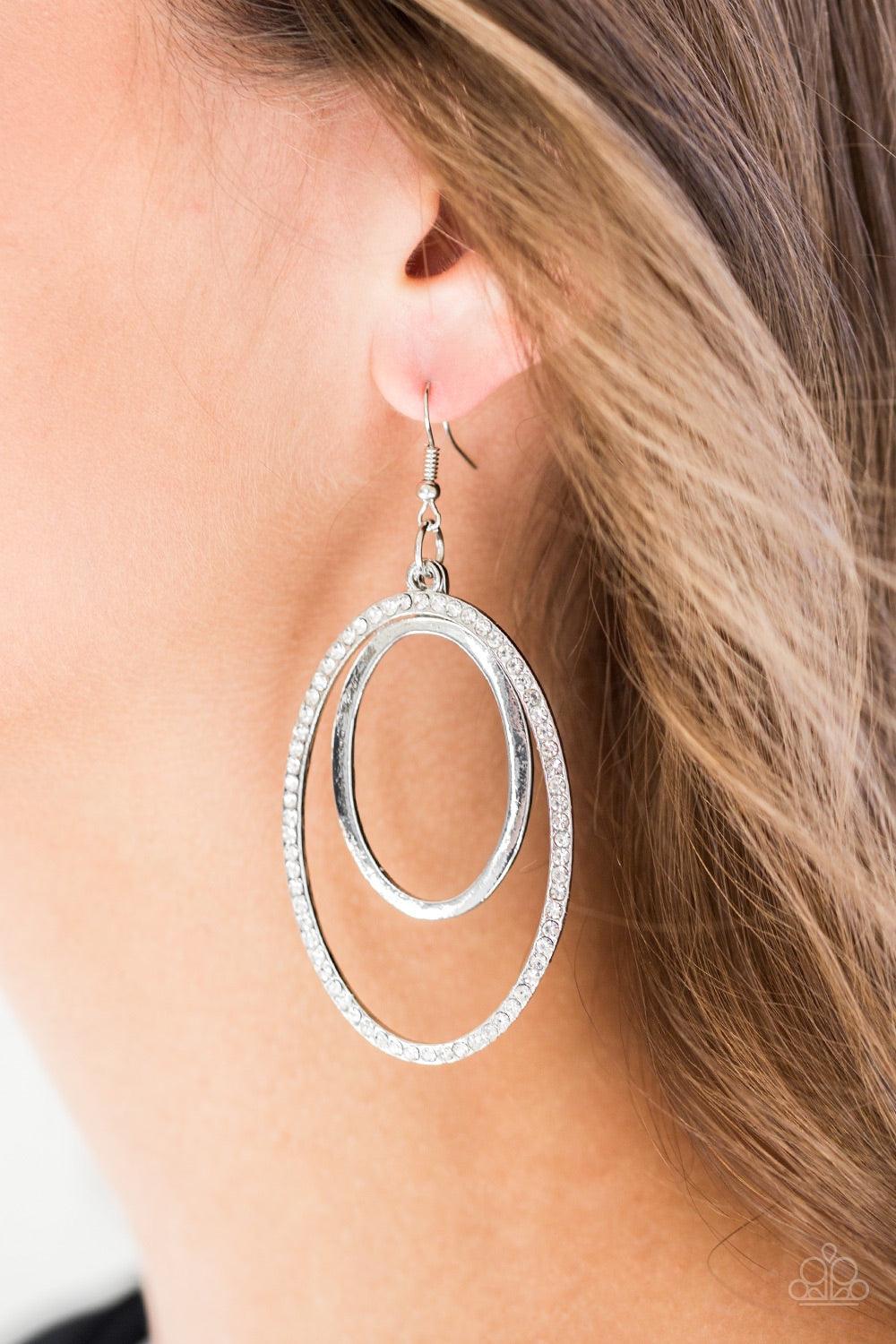 Paparazzi Accessories Wrapped in Wealth - White A glistening silver hoop swings from the top of a larger silver hoop radiating with glassy white rhinestones for a refined look. Earring attaches to a standard fishhook fitting. Jewelry