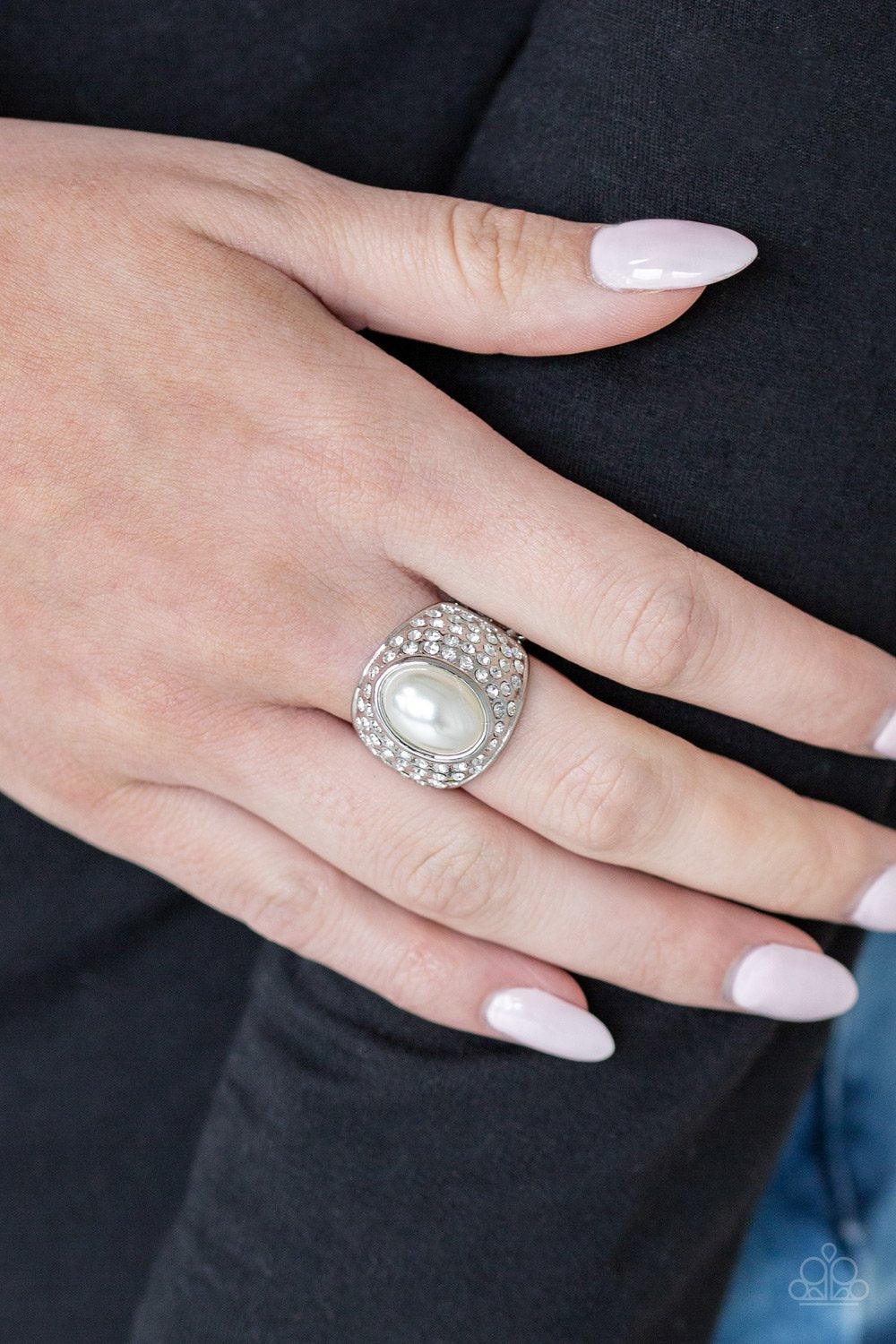 Paparazzi Accessories Glittering Go-Getter - White A pearly white bead is pressed into the center of a bold silver band radiating with countless white rhinestones, creating a dramatic statement piece atop the finger. Features a stretchy band for a flexibl