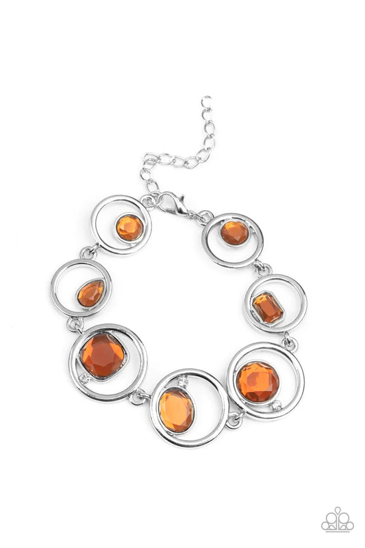 Paparazzi Accessories Date Night Drama - Brown Sporadically infused with dainty white rhinestones, a glittery collection of round, teardrop, and emerald cut topaz rhinestones haphazardly adorn the centers of interlocking silver hoops around the wrist for