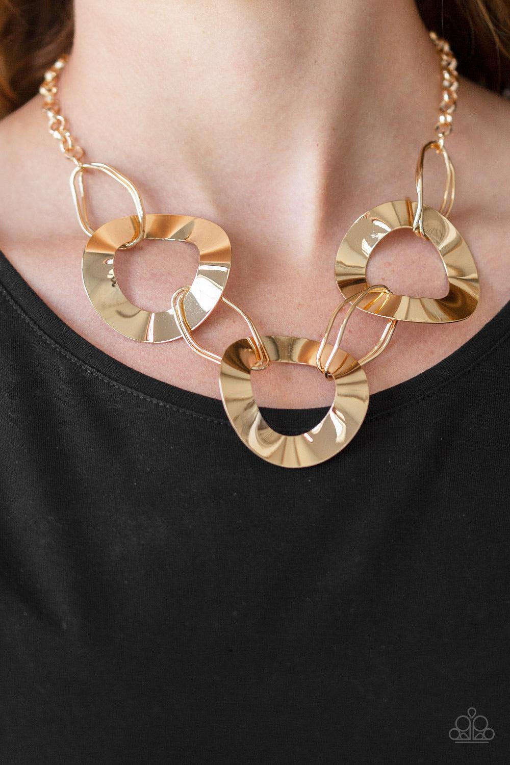 Paparazzi Accessories Modern Mechanics - Gold Featuring slightly warped surfaces, asymmetrical gold hoops link with reflective gold rings below the collar for a modern look. Features an adjustable clasp closure. Sold as one individual necklace. Includes o