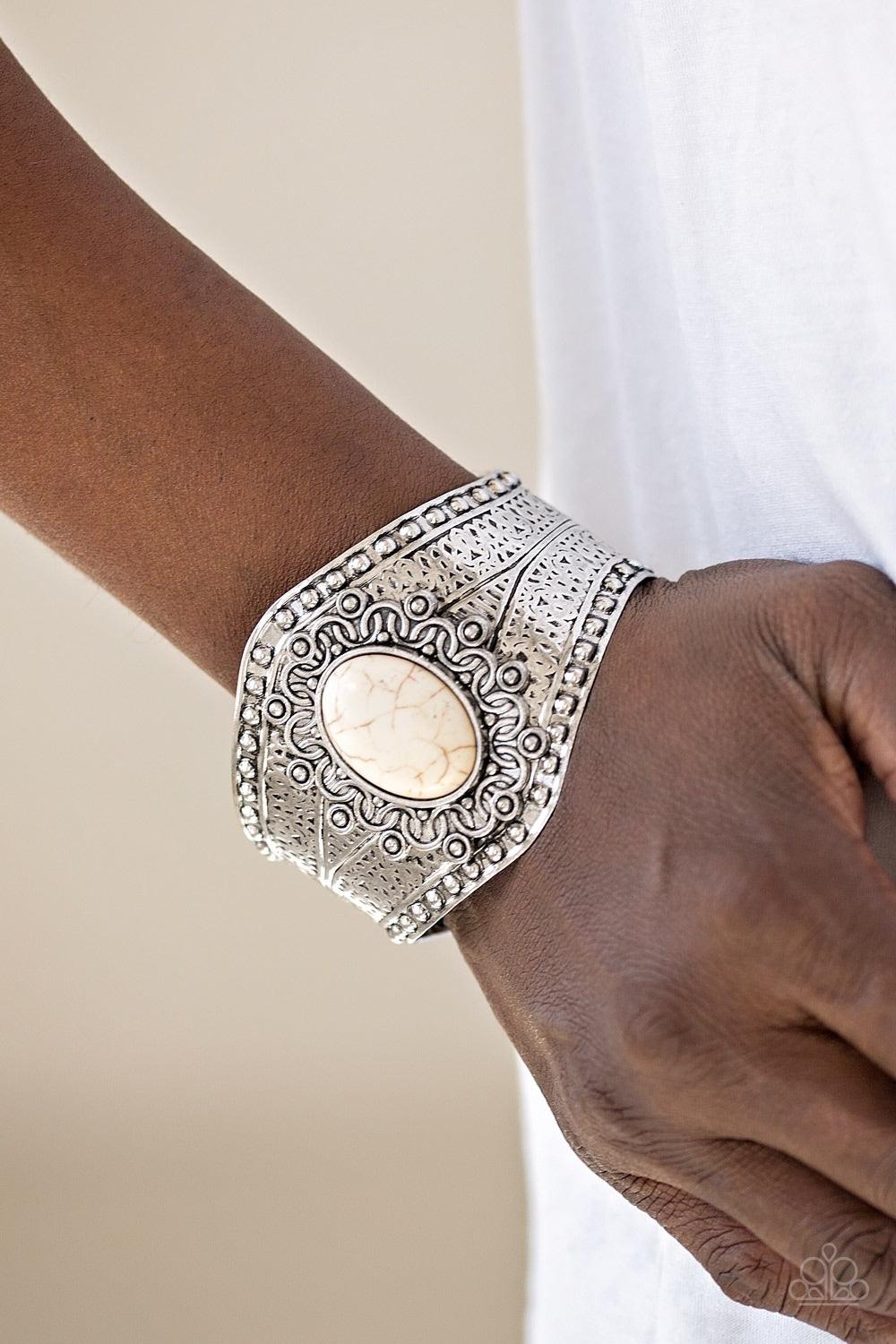 Paparazzi Accessories Majave Majesty - White Delicately hammered and studded in tribal inspired textures, a thick silver cuff wraps around the wrist in an artisan inspired fashion. A smooth white stone is pressed into the middle of a silver sunburst patte