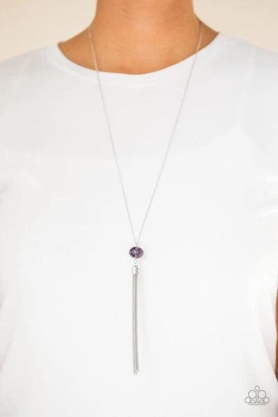 Paparazzi Accessories Socialite of the Season - Purple A glittery purple crystal-like bead swings from the bottom of a lengthened silver chain, giving way to a shimmering silver tassel for a glamorous finish. Features an adjustable clasp closure. Sold as