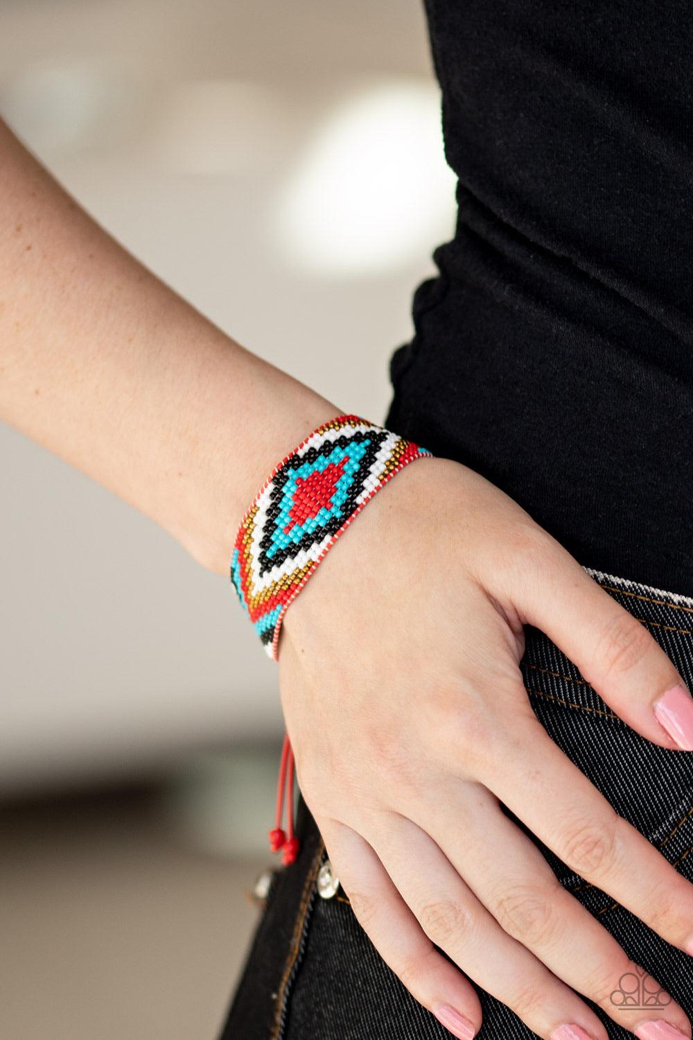 Paparazzi Accessories Beautifully Badlands - Red Threaded along invisible thread, a dainty collection of red, blue, black, brass, and white seed beads weave into a colorful textile pattern across the wrist for a tribal inspired look. Features an adjustabl