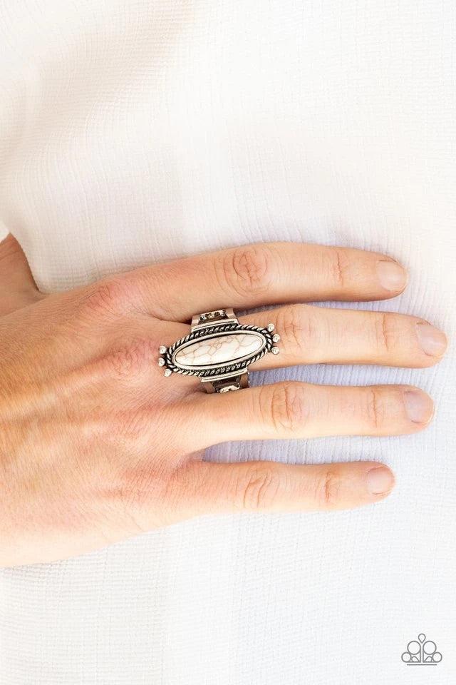 Paparazzi Accessories Sahara Escape - White An oblong white stone is pressed into the center of a rustic silver frame radiating with studded and metallic ropelike textures, creating a seasonal centerpiece atop the finger. Features a stretchy band for a fl