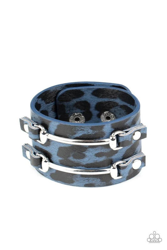 Paparazzi Accessories Safari Scene - Blue Two arcing silver bars are studded in place across the front of a thick leather band painted in blue and black cheetah print for a wild look. Features an adjustable snap closure. Sold as one individual bracelet. J