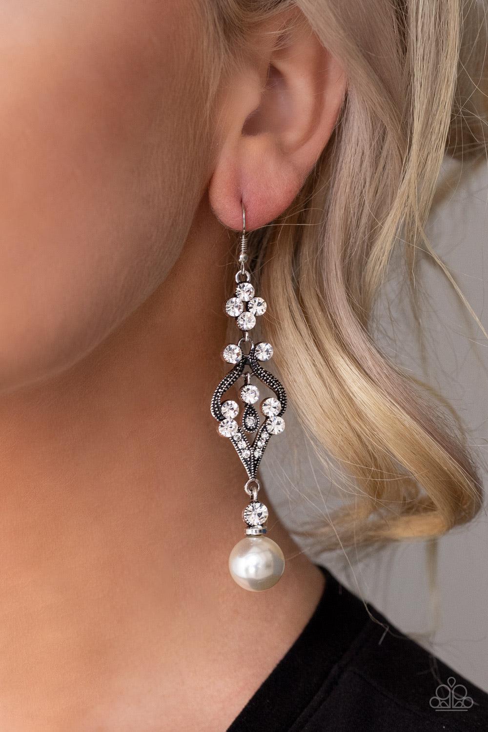 Paparazzi Accessories Elegantly Extravagant - White An oversized white pearl dangles from the bottom of a flowery silver frame dotted in sections of glassy white rhinestones for an elegant look. Earring attaches to a standard fishhook fitting. Jewelry