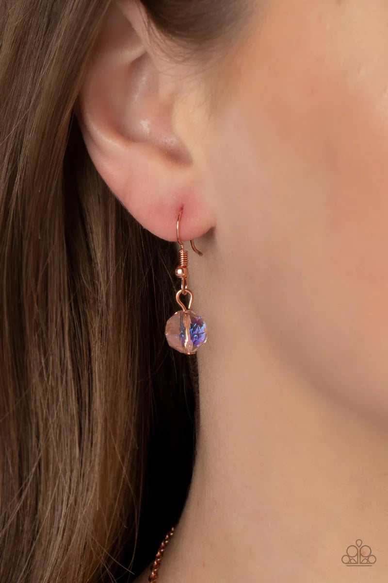Paparazzi Accessories Tasteful Teardrops - Copper An iridescent peach crystal-like bead twinkles from the top of two mismatched shiny copper teardrop frames at the bottom of an extended shiny copper chain, resulting in a tasteful and timeless pendant. Fea