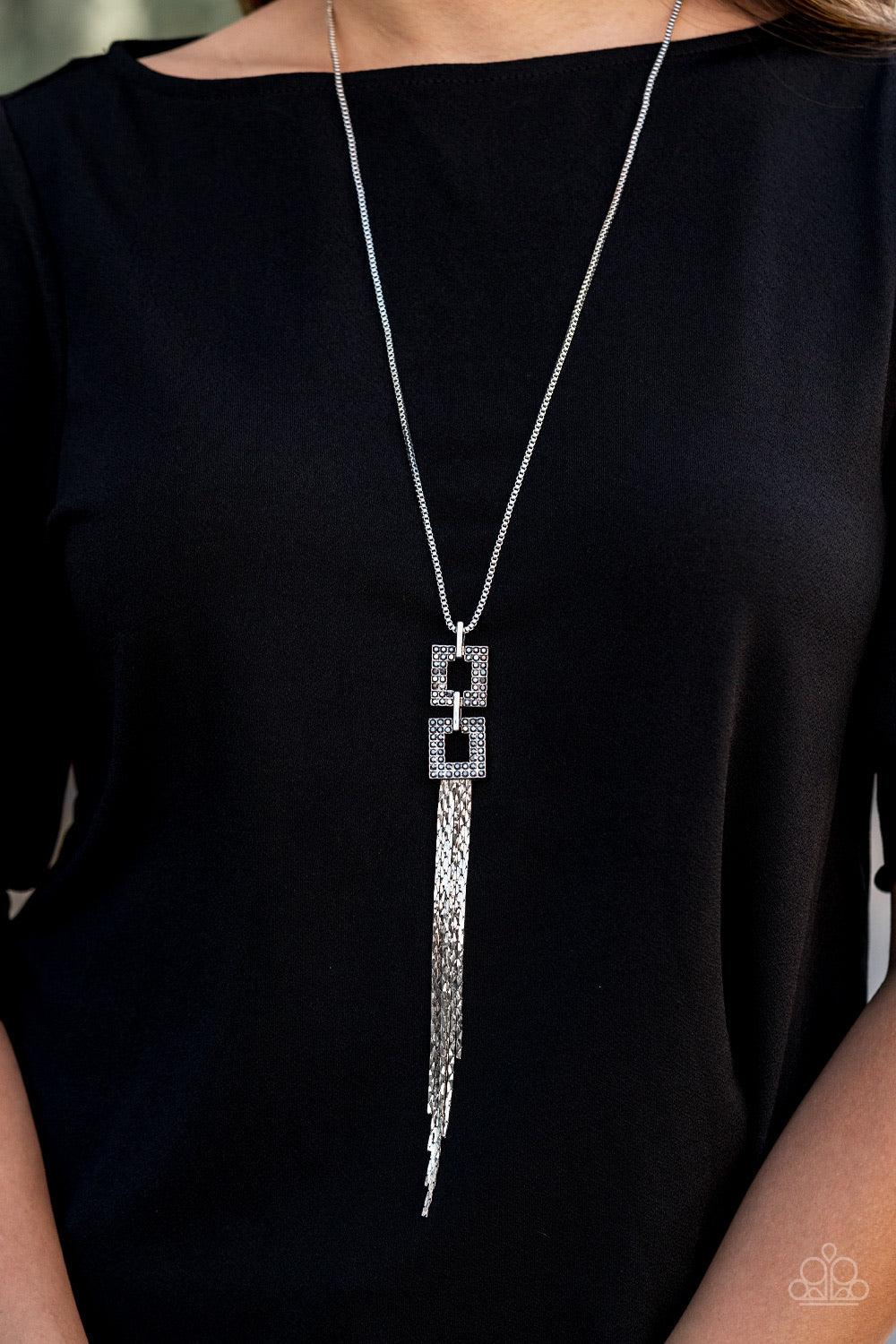 Paparazzi Accessories Times Square Stunner - Silver Encrusted in smoky hematite rhinestones, two squared, silver frames link at the bottom of a lengthened silver box chain. Flattened silver chains stream from the bottom of the stacked pendant, creating an