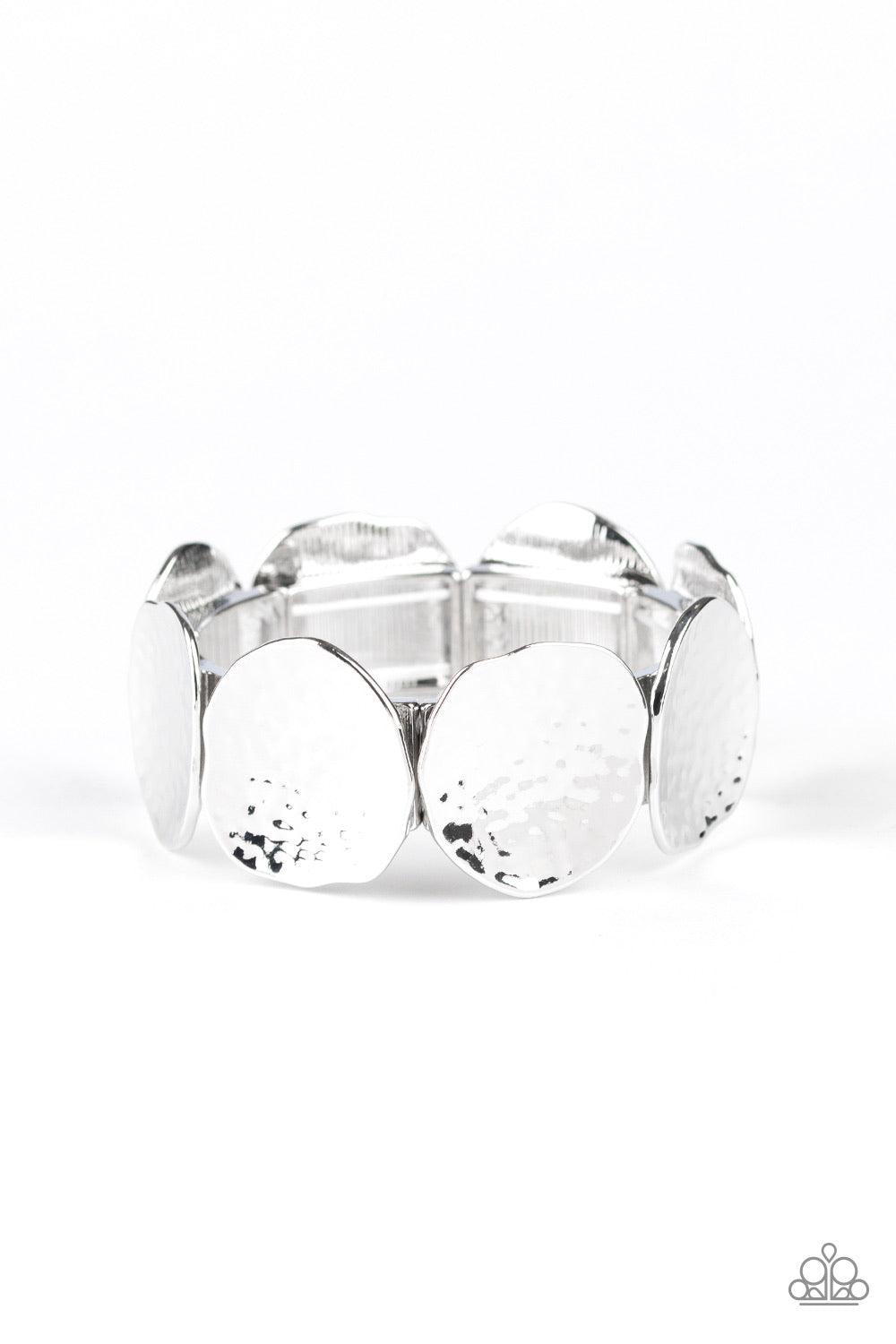 Paparazzi Accessories Treasure Cache - Silver Delicately hammered in shimmer, asymmetrical silver discs are threaded along a stretchy band around the wrist for an edgy look. Jewelry