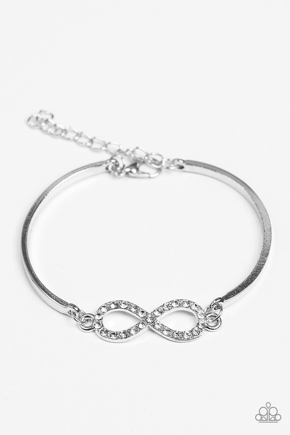 Paparazzi Accessories Infinite Treasure - White Two arching silver bars are separated by a shimmery infinity charm. Encrusted with dainty white rhinestones, the dainty charm delicately links with the silver bars, creating the illusion of a floating center