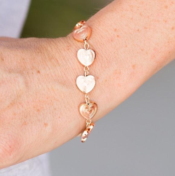 Paparazzi Accessories No Heart Feelings - Rose Gold Engraved in rippling heart patterns, glistening rose gold hearts link across the wrist in a casual fashion. Features an adjustable clasp closure. Jewelry