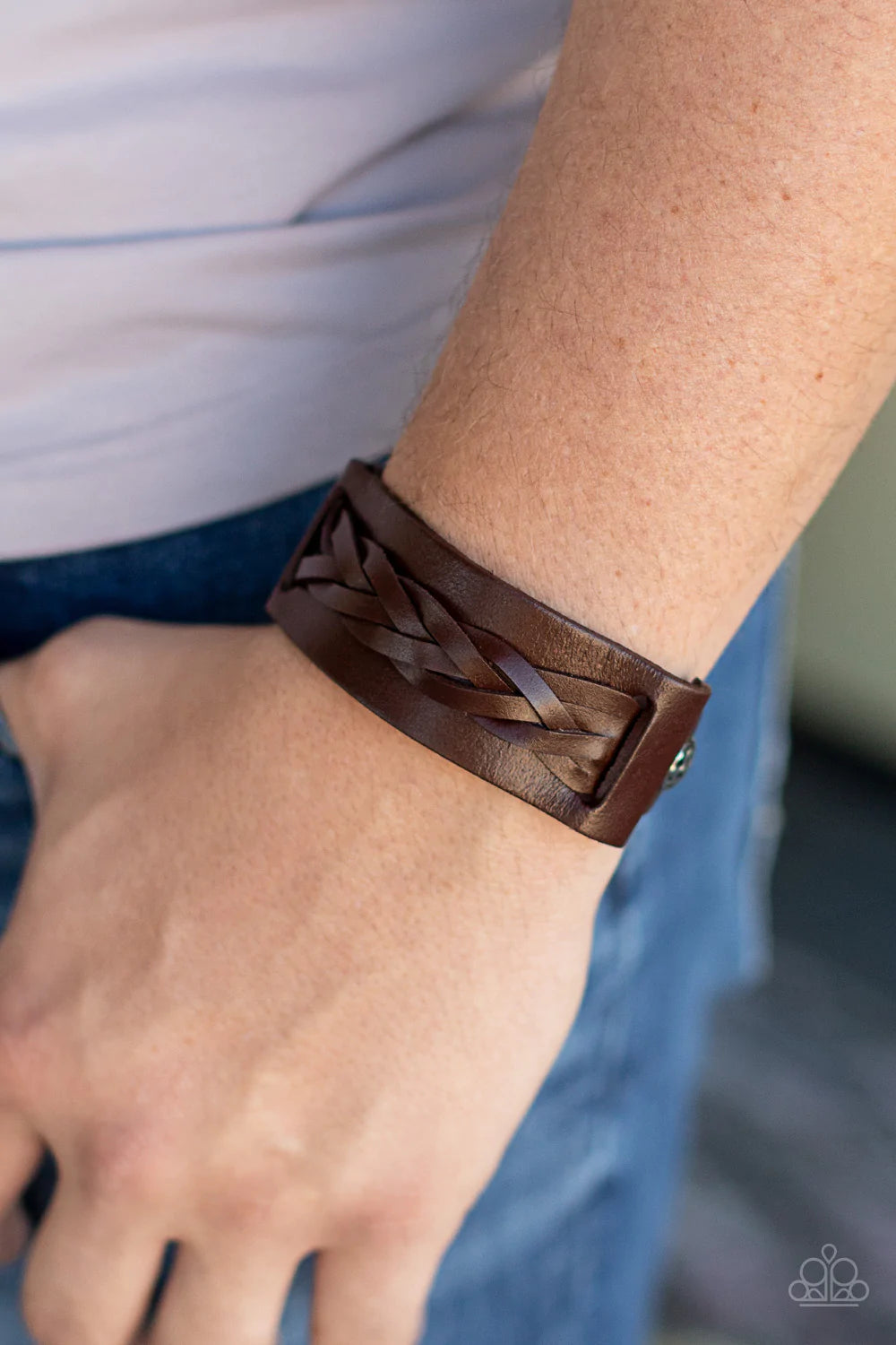 Paparazzi Accessories Practical Pioneer - Brown Braided strands of brown leather laces are studded in place across the front of a thick brown leather band with hammered silver studs, creating a rustic centerpiece around the wrist. Features an adjustable b