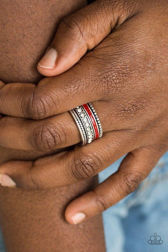 Paparazzi Accessories Rich Rogue - Red A shiny red strip of color runs along the bottom of a row of glassy white rhinestones. Infused with silver textures, the mismatched details coalesce into one thick band across the finger. Features a stretchy band for