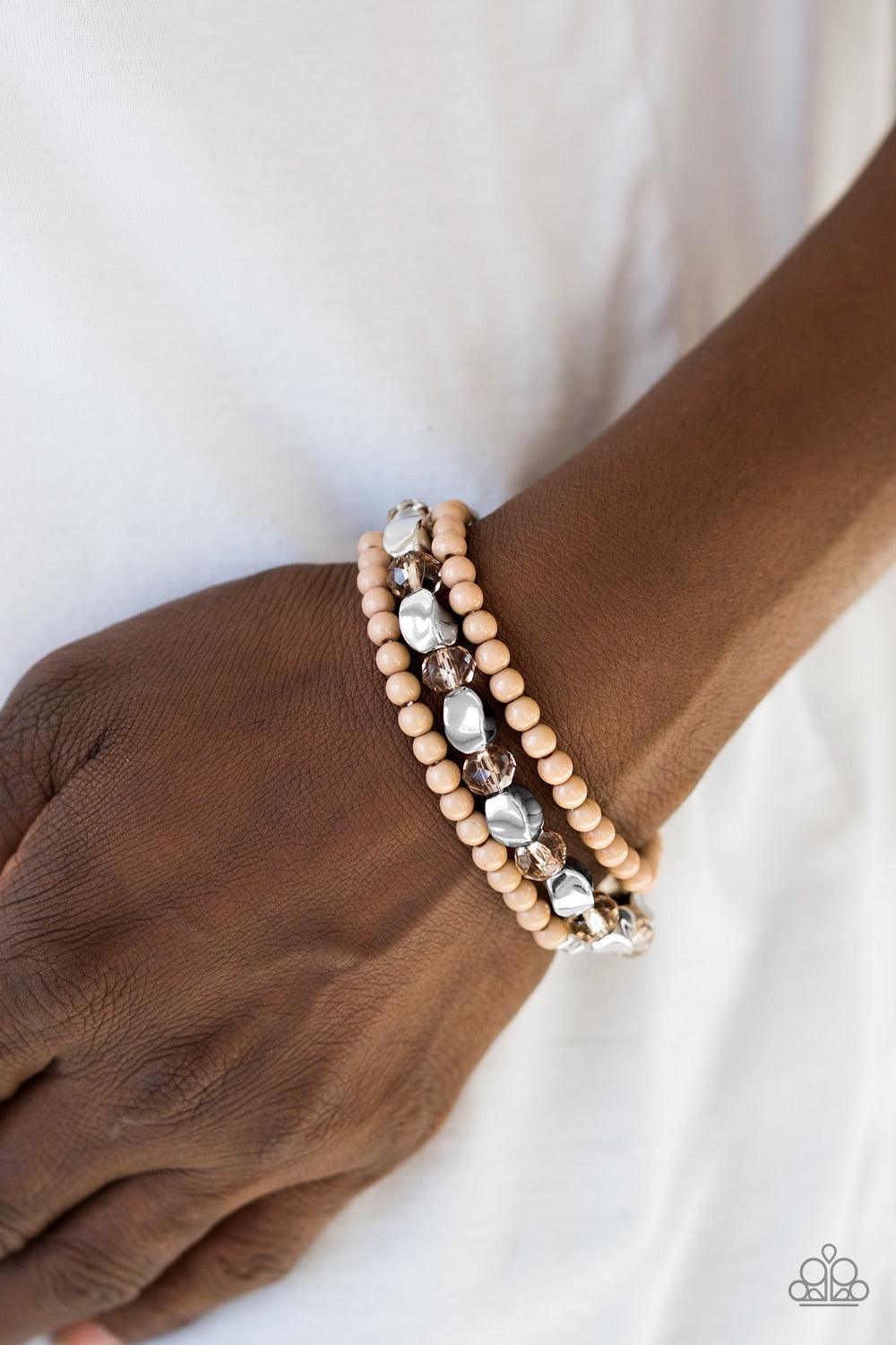 Paparazzi Accessories Beaded Bravado - Brown Varying in shape and shimmer, faceted silver beads, dainty brown beads, and glittery crystal-like beads are threaded along elastic stretchy bands, creating colorful layers across the wrist. Jewelry