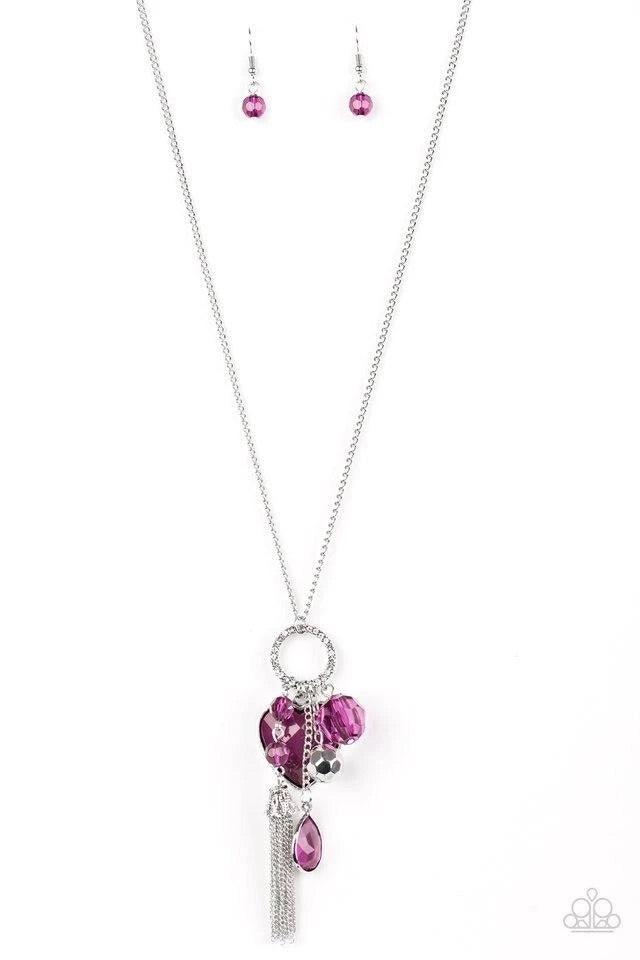 Paparazzi Accessories Haute Heartbreaker - Purple Infused with a lengthened silver chain, an array of glassy purple and shimmery silver accents swing from the bottom of a white rhinestone encrusted frame. A faceted purple heart frame swings from the botto