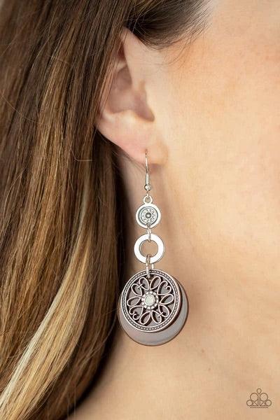 Paparazzi Accessories Royal Marina - Brown Reminiscent of an eclipse, an airy silver ring radiating with ornate petals, sways in front of a brown shell-like disc. Silver rings in graduating sizes cascade from the top for a whimsically nautical look. Earri