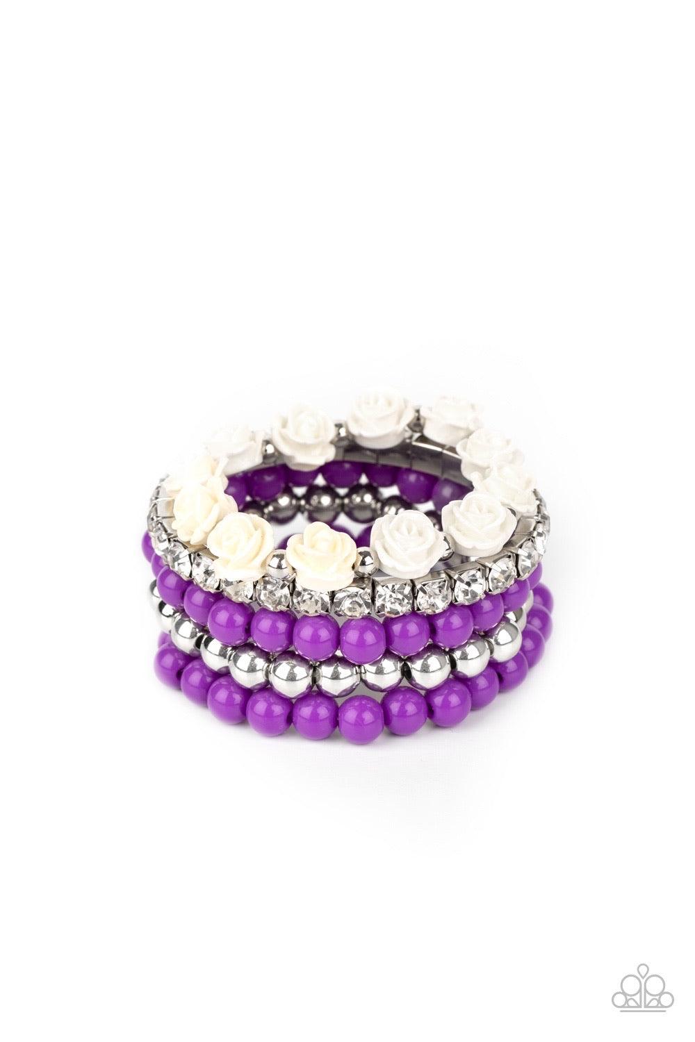 Paparazzi Accessories Rose Garden Grandeur - Purple A vintage inspired collection of white resin roses, purple beads, and classic silver beads join a stretchy band of glittery white rhinestones dotted around the wrist for a flawlessly stacked look. Sold a