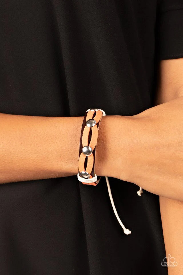 Paparazzi Accessories Ready to Ride - Orange Loops of orange suede are studded and knotted in place across the front of a brown leather band, resulting in a spirted southwestern display around the wrist. Features an adjustable sliding knot closure. Jewelr