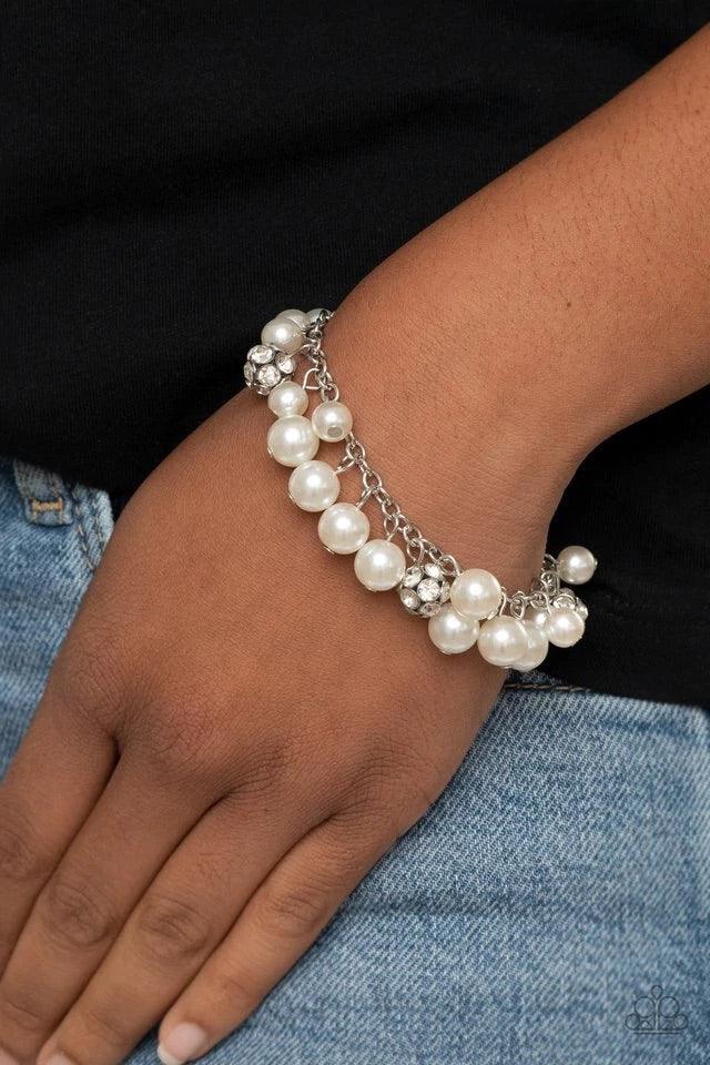 Paparazzi Accessories The GRANDEUR Tour - White A timeless collection of bubbly white pearls and white rhinestone encrusted silver beads swing from a classic silver chain, creating a refined fringe. Features an adjustable clasp closure. Bracelets