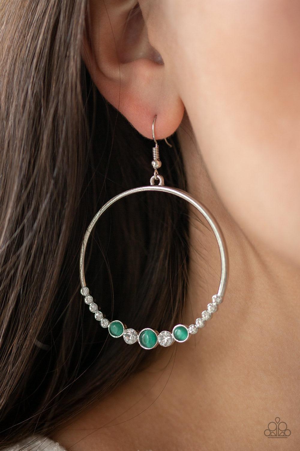 Paparazzi Accessories Dancing Radiance - Green A collection of glittery white rhinestones and glowing green cat's eye stones are encrusted along the bottom of a glistening silver hoop for a refined look. Earring attaches to a standard fishhook fitting. So