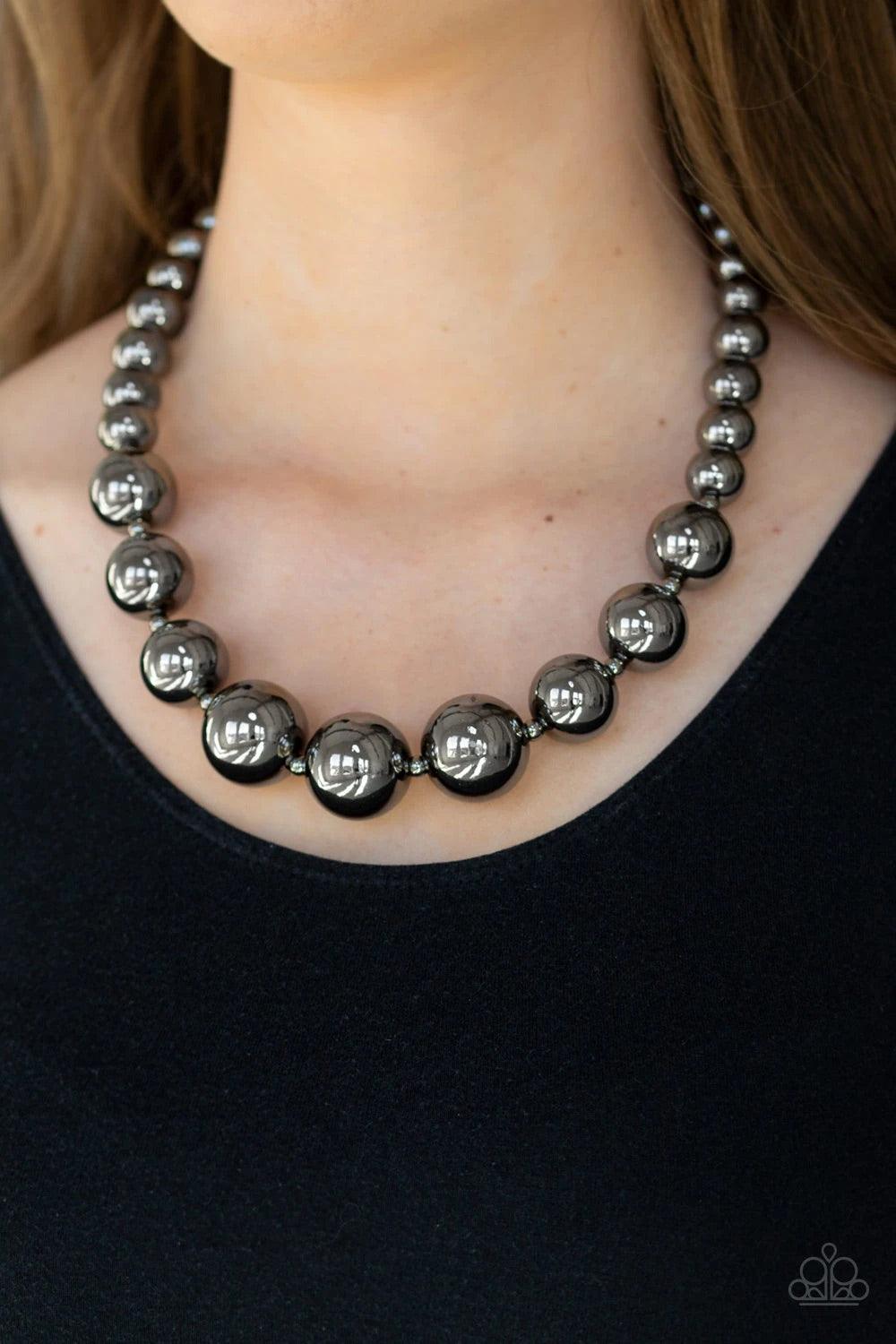Paparazzi Accessories Living Up To Reputation - Black A collection of bold gunmetal beads are threaded along an invisible wire below the collar. The glistening beads dramatically increase in size as they reach the center for an undeniable statement-making