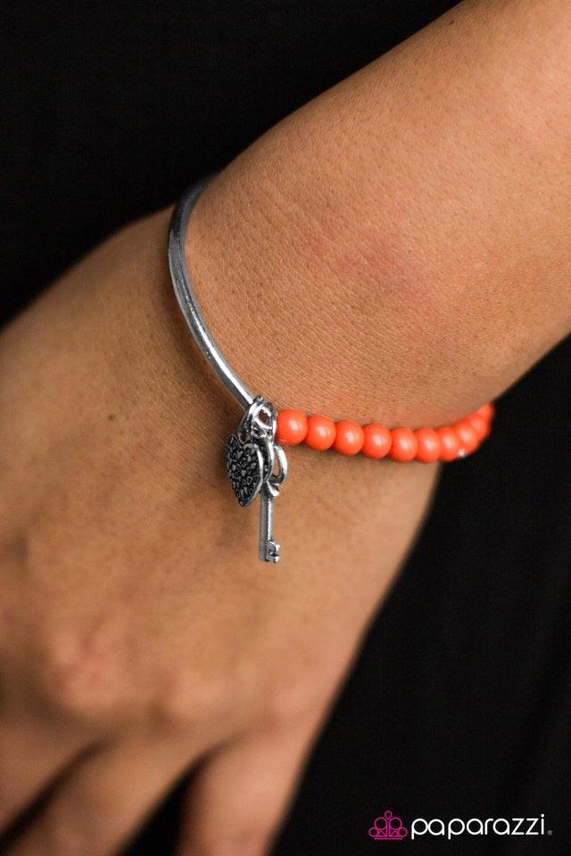 Paparazzi Accessories You Hold The Key ~Orange Threaded through an elastic stretchy band, orange beading connects to a silver bar around the wrist. Brushed in an antiqued shimmer, silver hearts, a key, and charm engraved in the word “love” slides along th