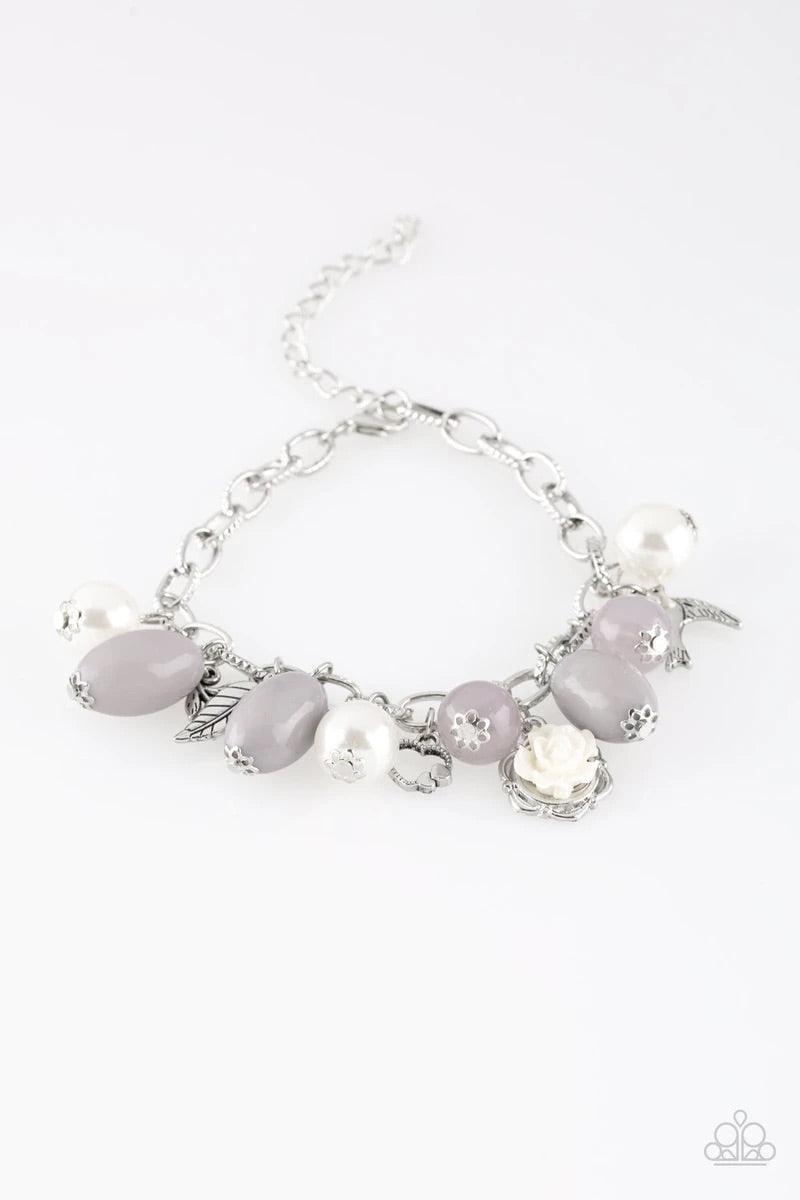 Paparazzi Accessories Love Doves - Silver Gorgeous pearls, luminescent gray beading, and a collection of shiny silver charms, including a bird and a feather, dance around the wrist in a whimsical fashion. Features an adjustable clasp closure. Sold as one